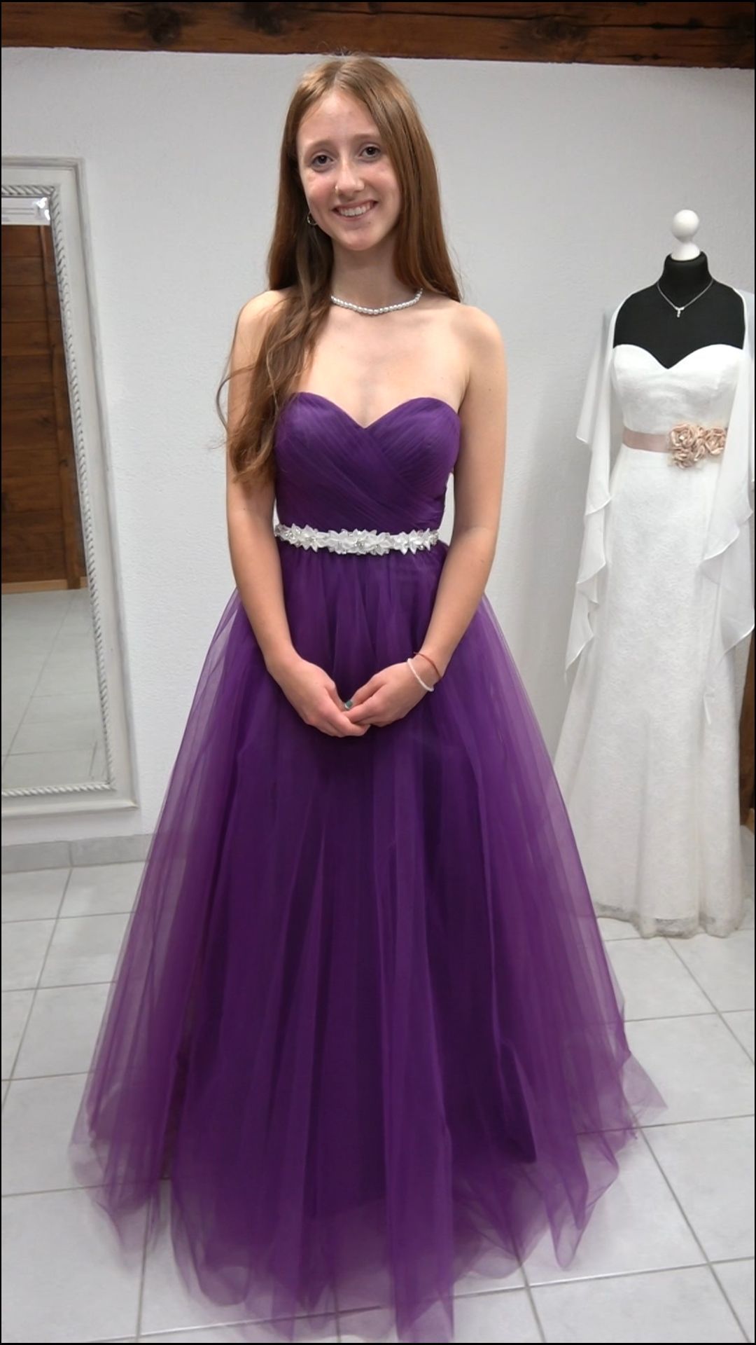 Eine Frau in einem lila Kleid steht vor einer Schaufensterpuppe, die ein weißes Kleid trägt.