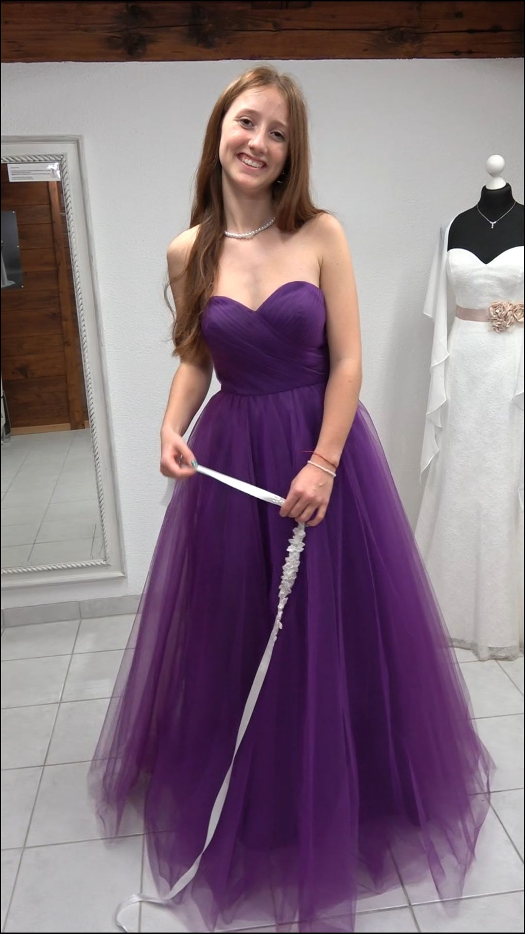 Eine Frau in einem lila Kleid misst ihr Kleid mit einem Maßband.