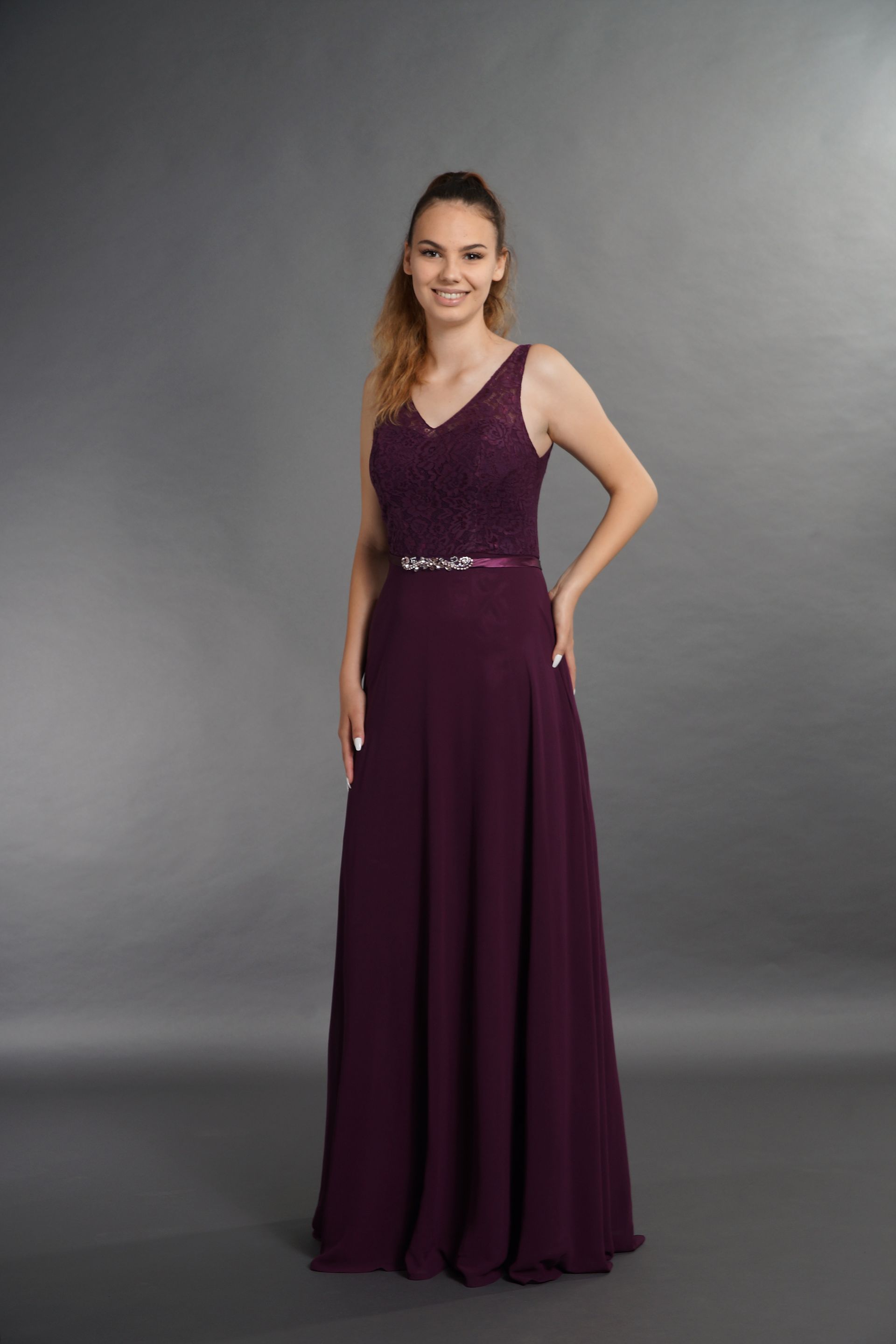 Eine Frau trägt ein langes lila Kleid und lächelt.