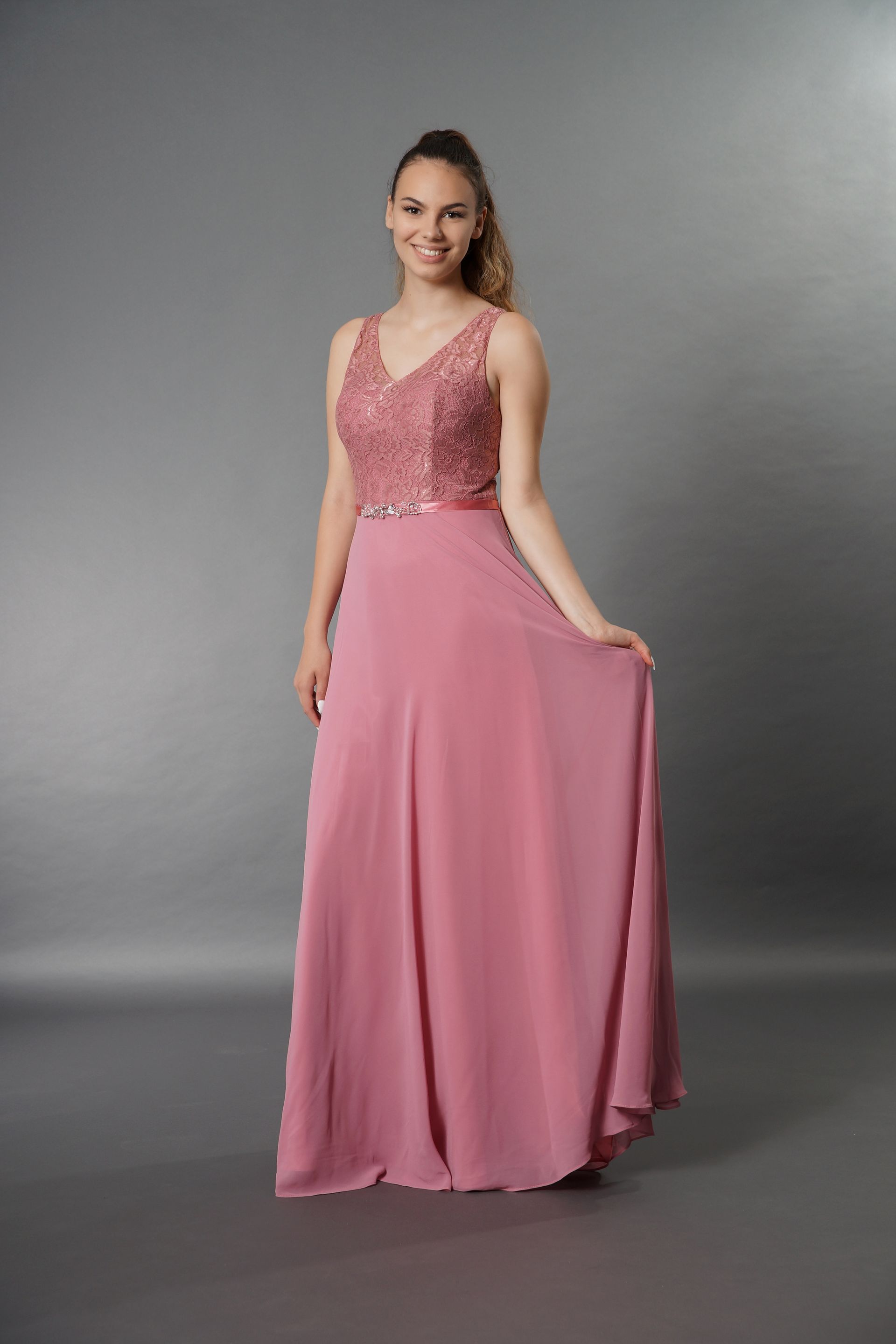 Eine Frau trägt ein langes rosa Kleid mit einem Spitzenoberteil.