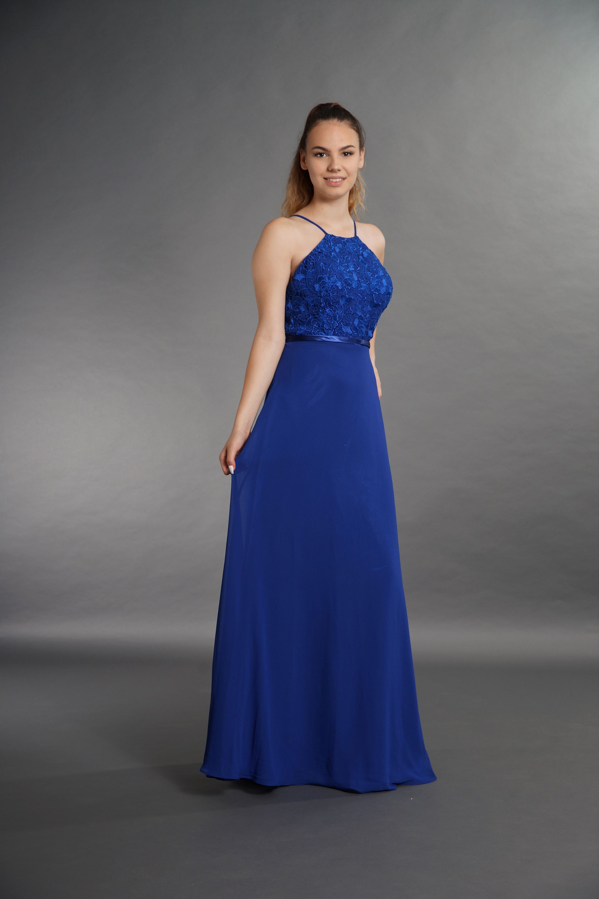 Eine Frau trägt ein langes blaues Kleid mit einem Spitzenoberteil.