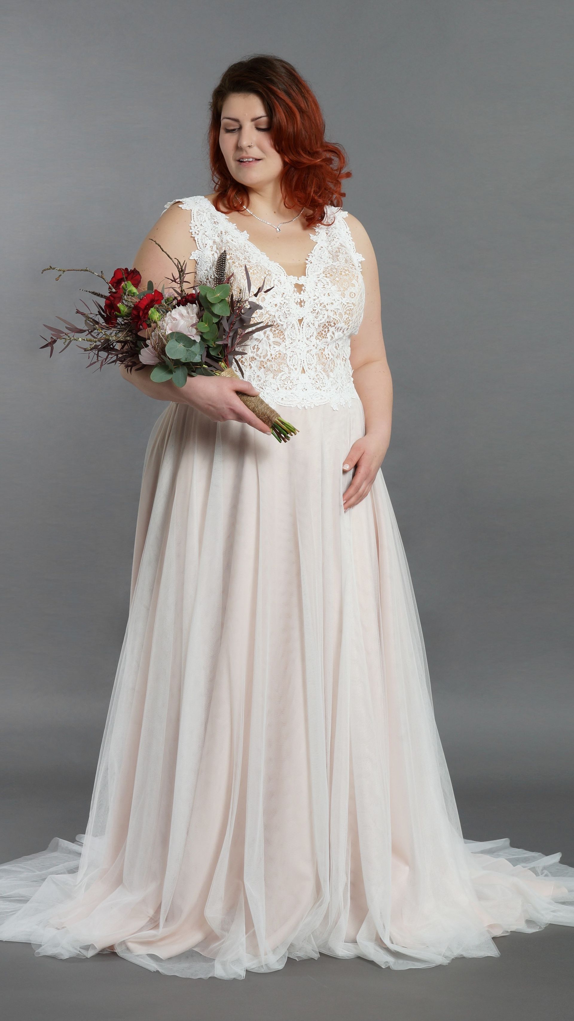 Eine Frau in einem Brautkleid hält einen Blumenstrauß.