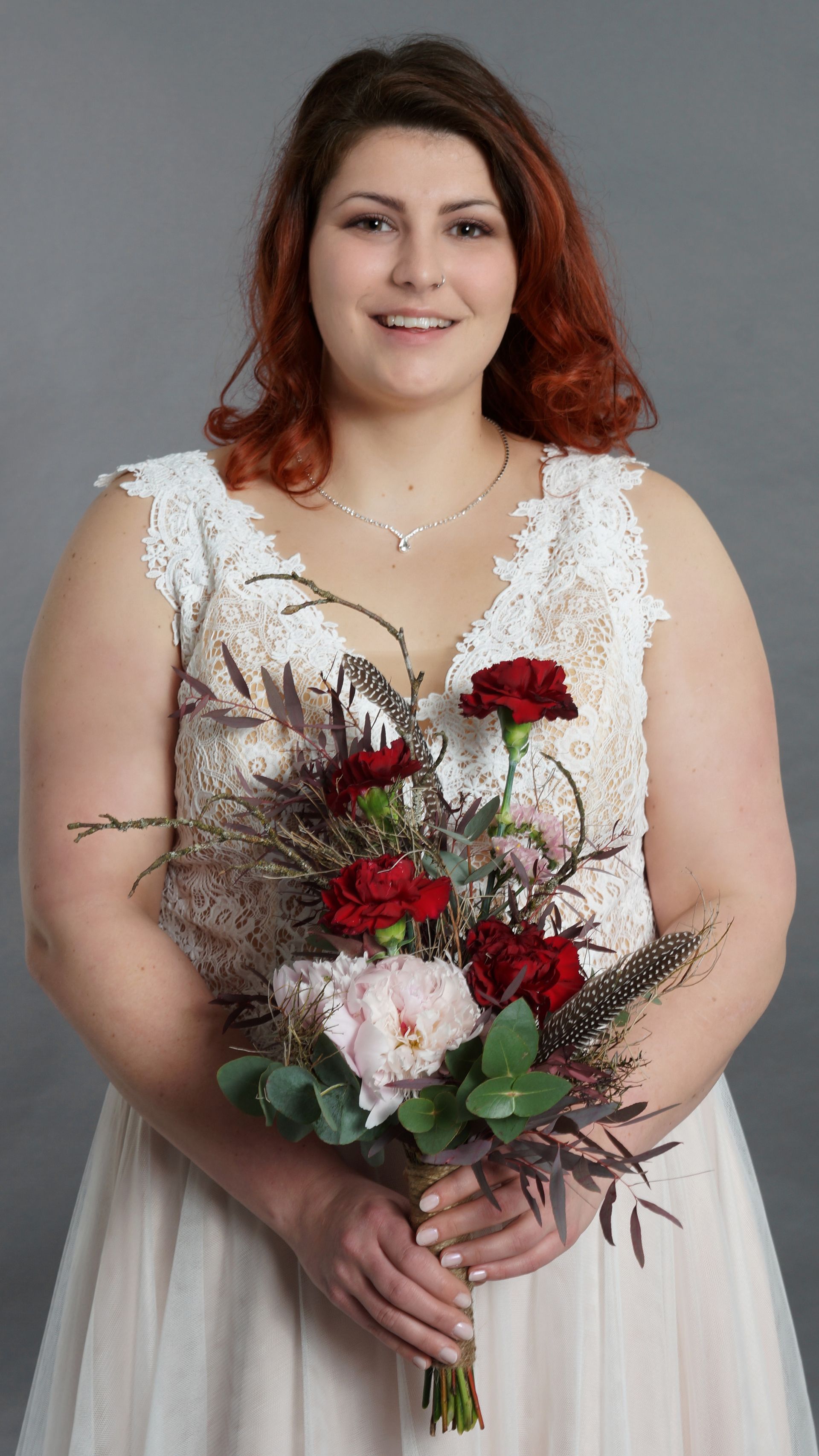 Eine Frau in einem Brautkleid hält einen Blumenstrauß.