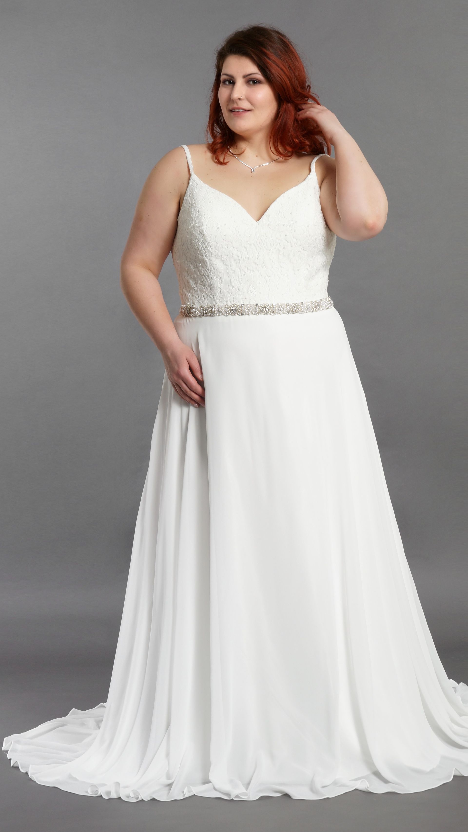 Eine Frau mit Übergröße trägt ein weißes Brautkleid.