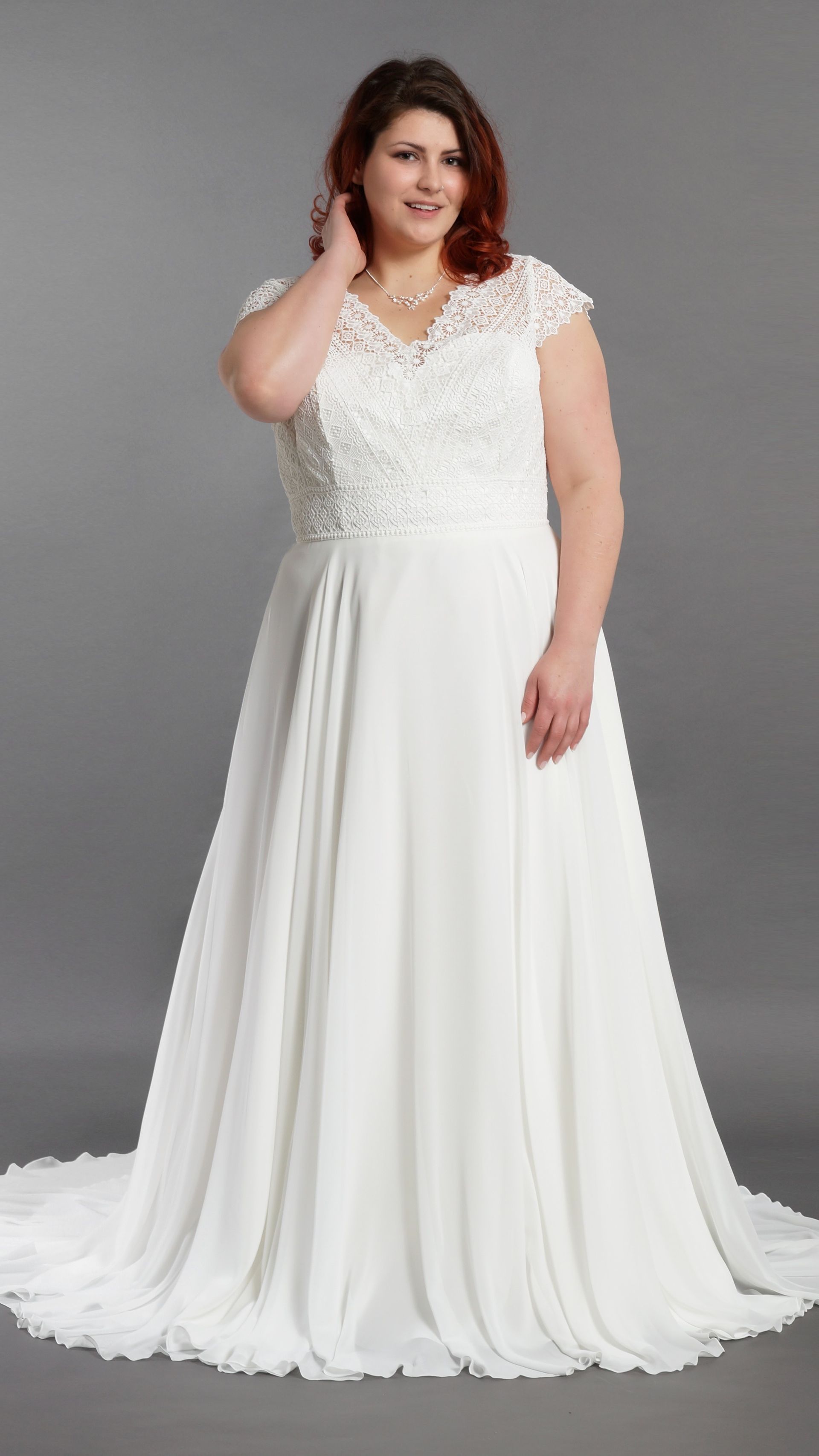 Eine Frau mit Übergröße trägt ein weißes Brautkleid.