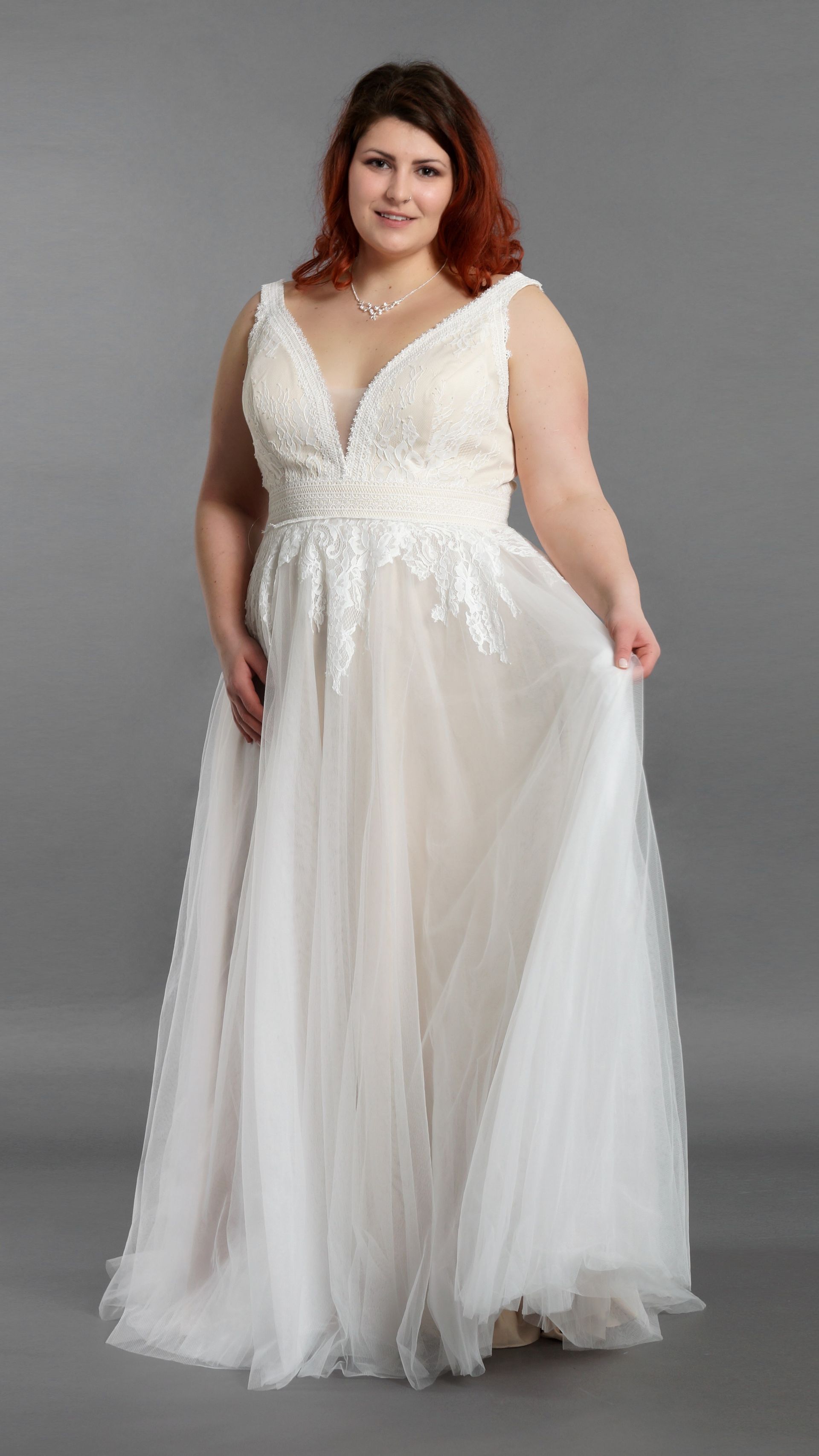 Eine Frau mit Übergröße trägt ein weißes Brautkleid.