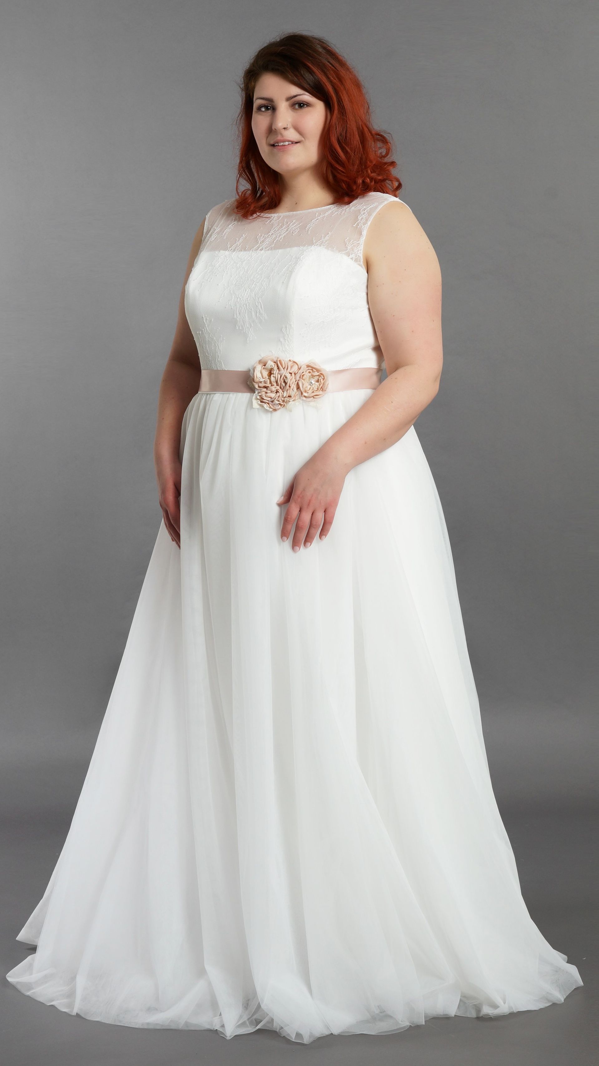 Eine Frau mit Übergröße trägt ein weißes Brautkleid.