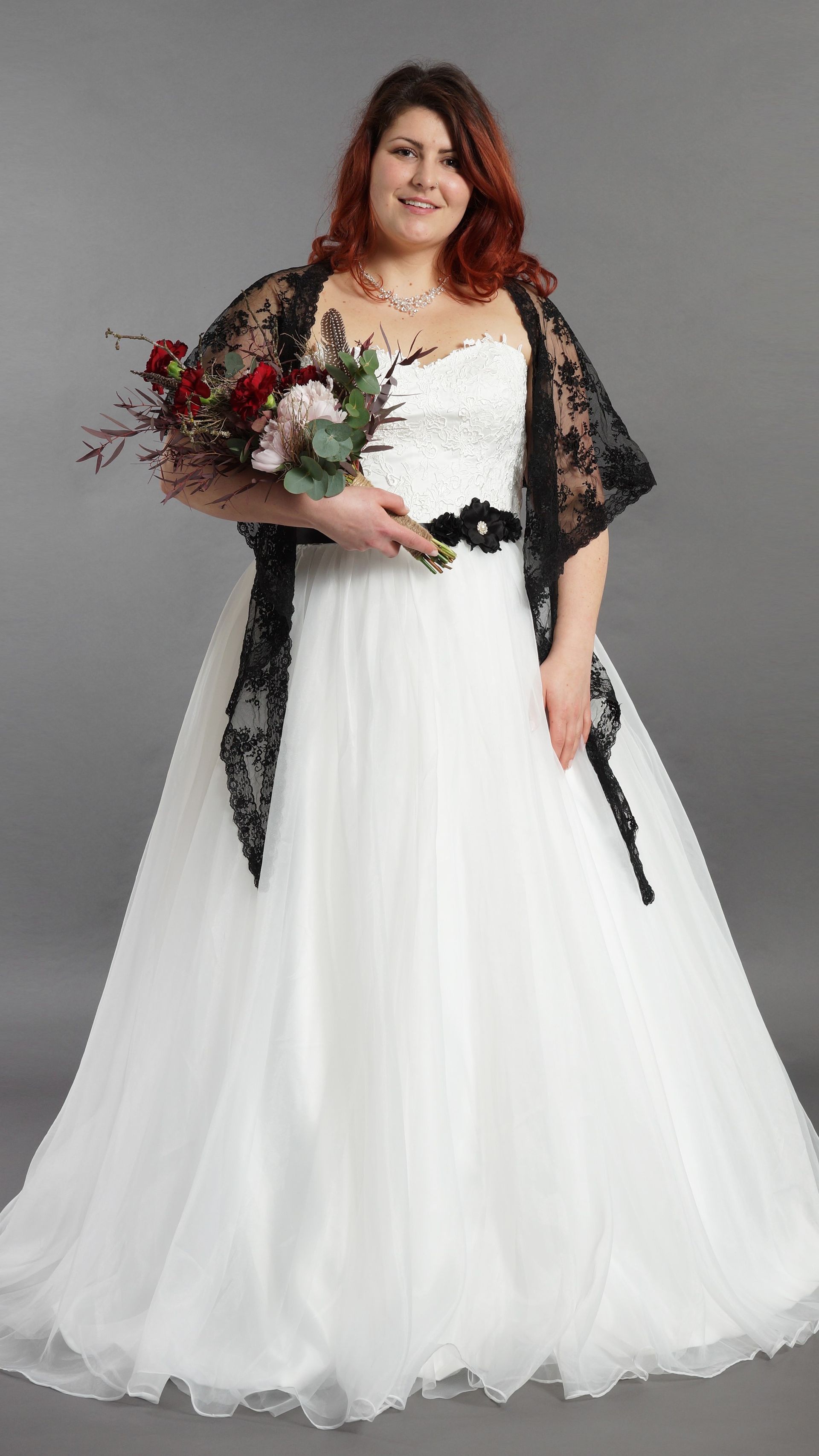 Eine Frau in einem weißen Brautkleid hält einen Blumenstrauß.