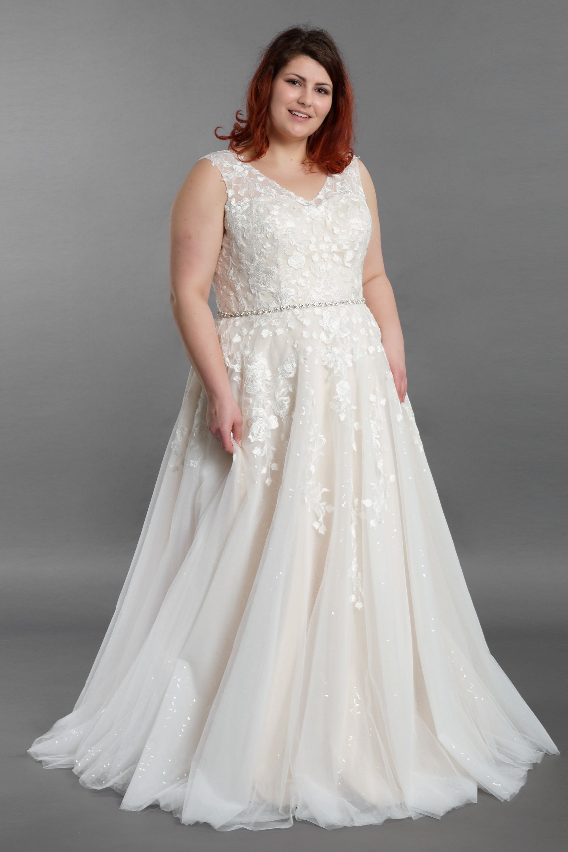 Eine Frau mit Übergröße trägt ein weißes Brautkleid.