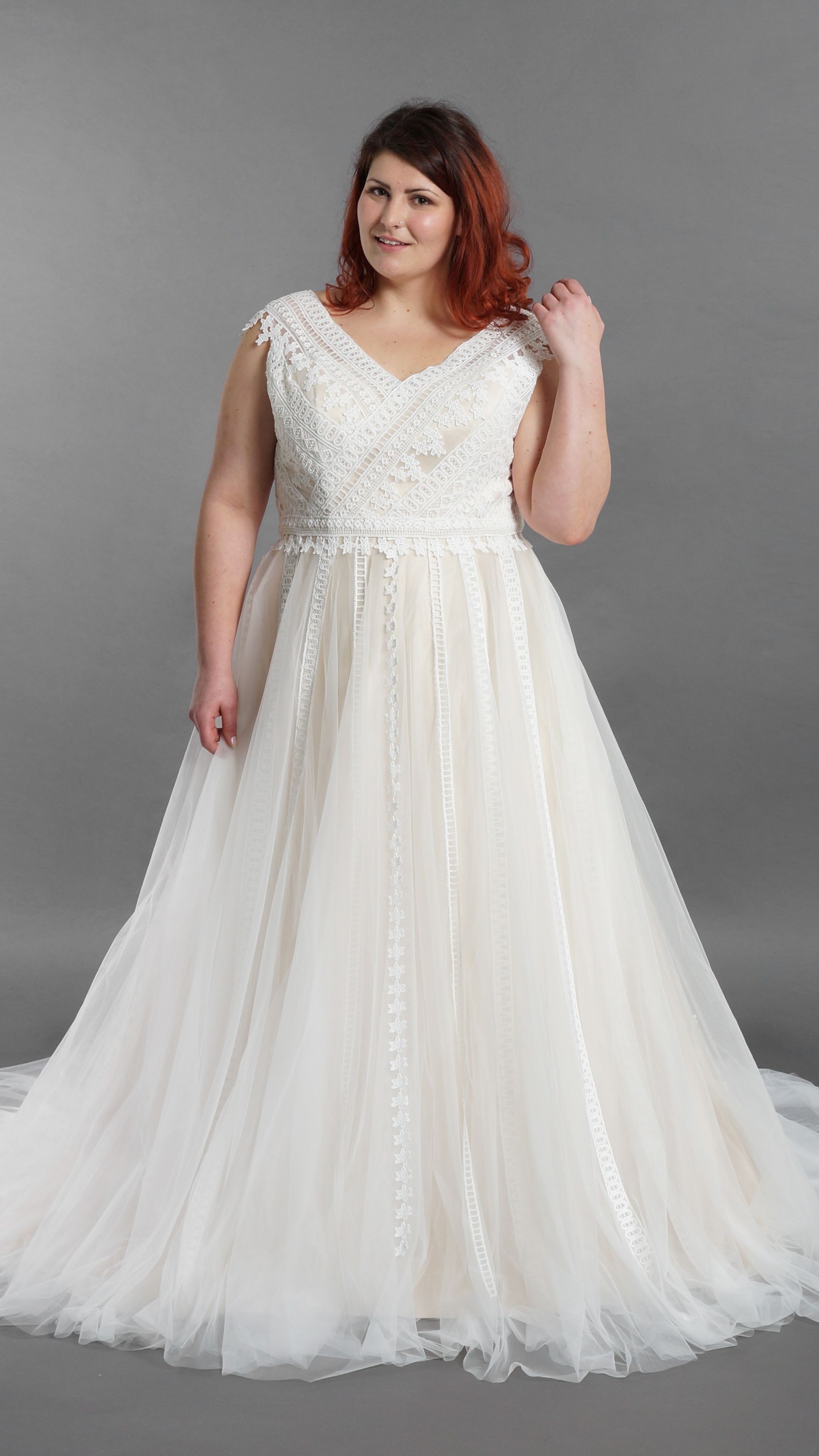 Eine Frau mit Übergröße trägt ein weißes Brautkleid.