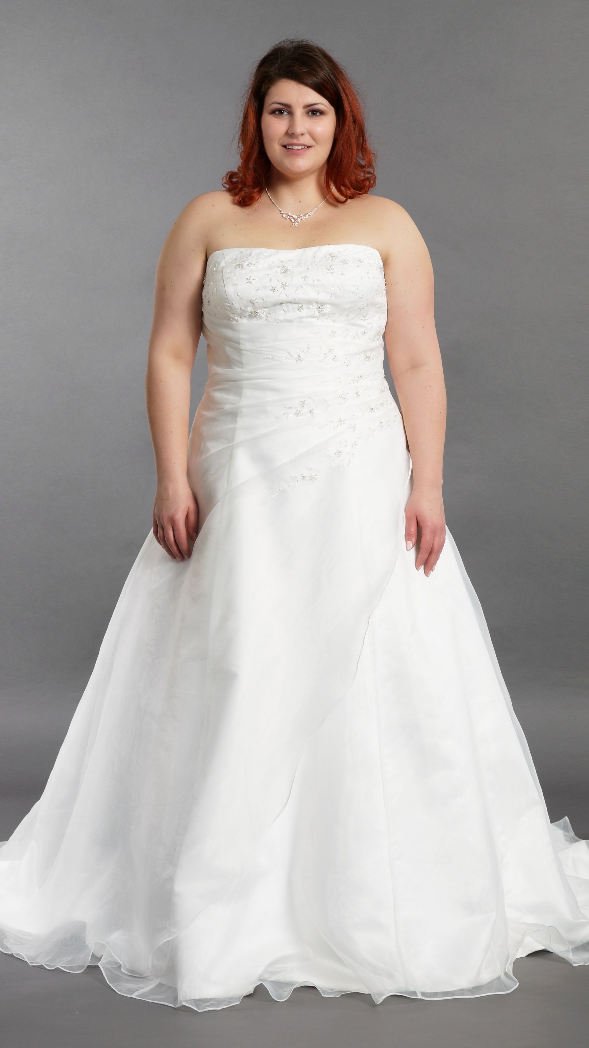 Eine Frau mit Übergröße trägt ein weißes Brautkleid.