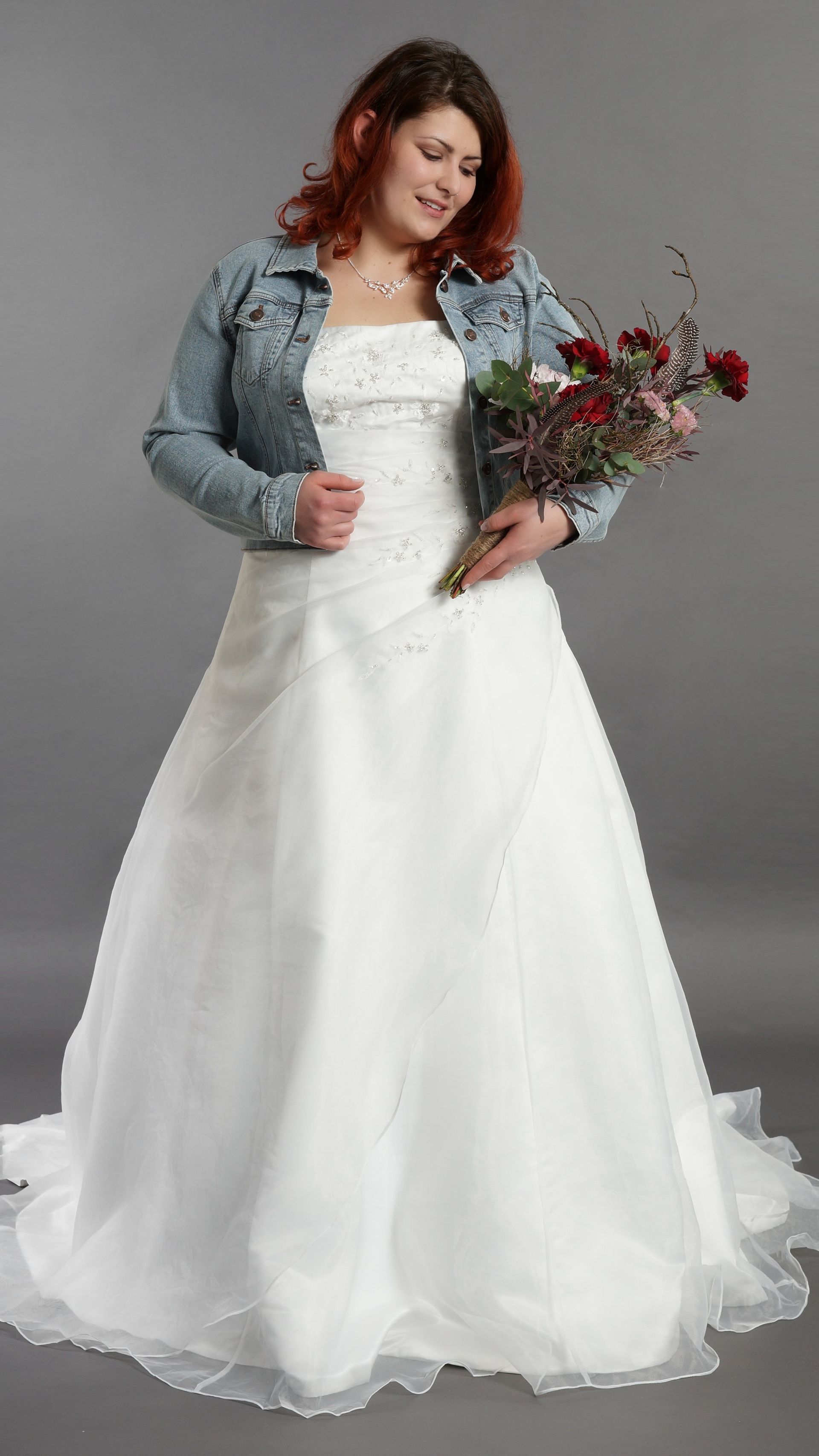 Eine Frau in einem weißen Brautkleid hält einen Blumenstrauß.