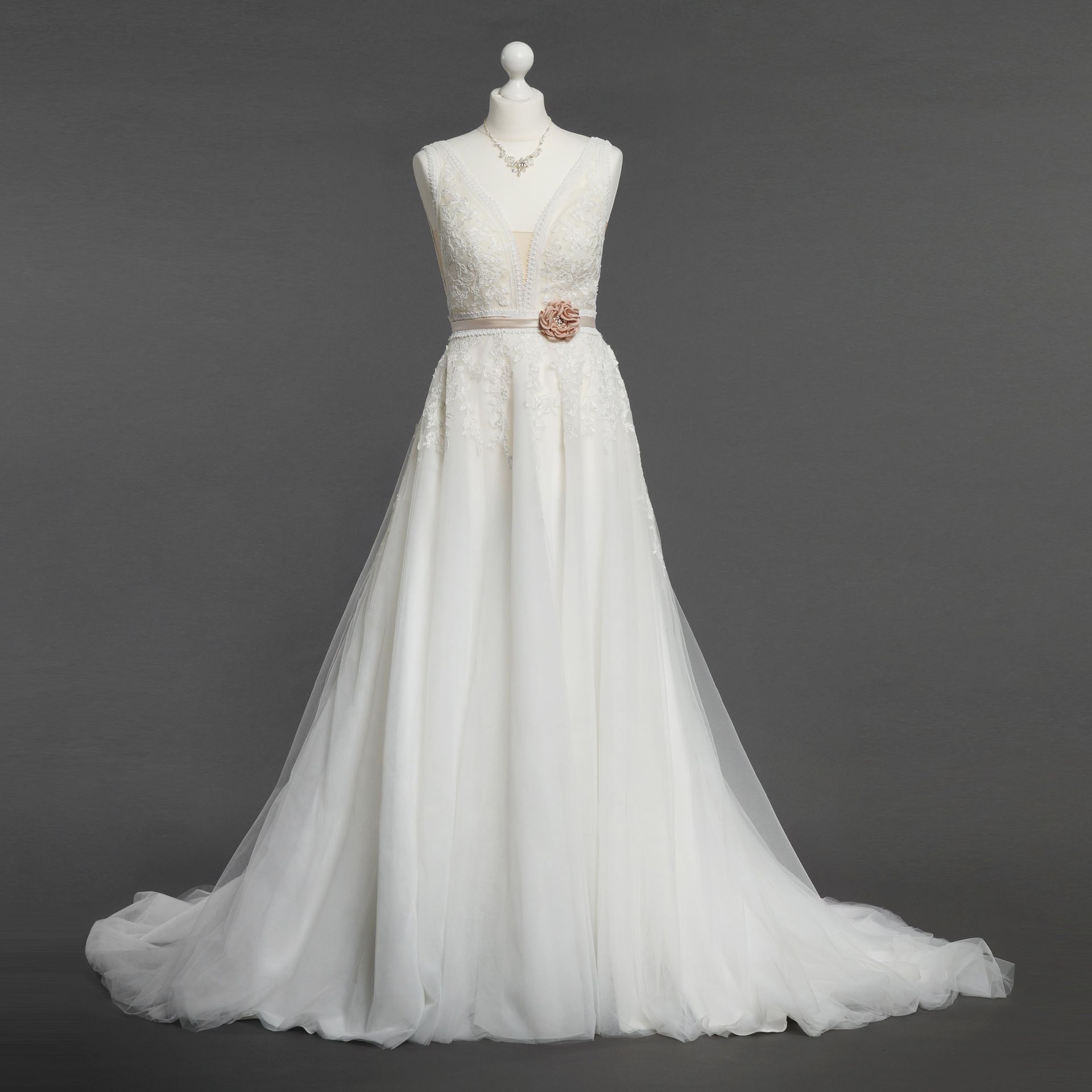 Ein weißes Brautkleid mit einer Blume an der Taille ist auf einer Schaufensterpuppe