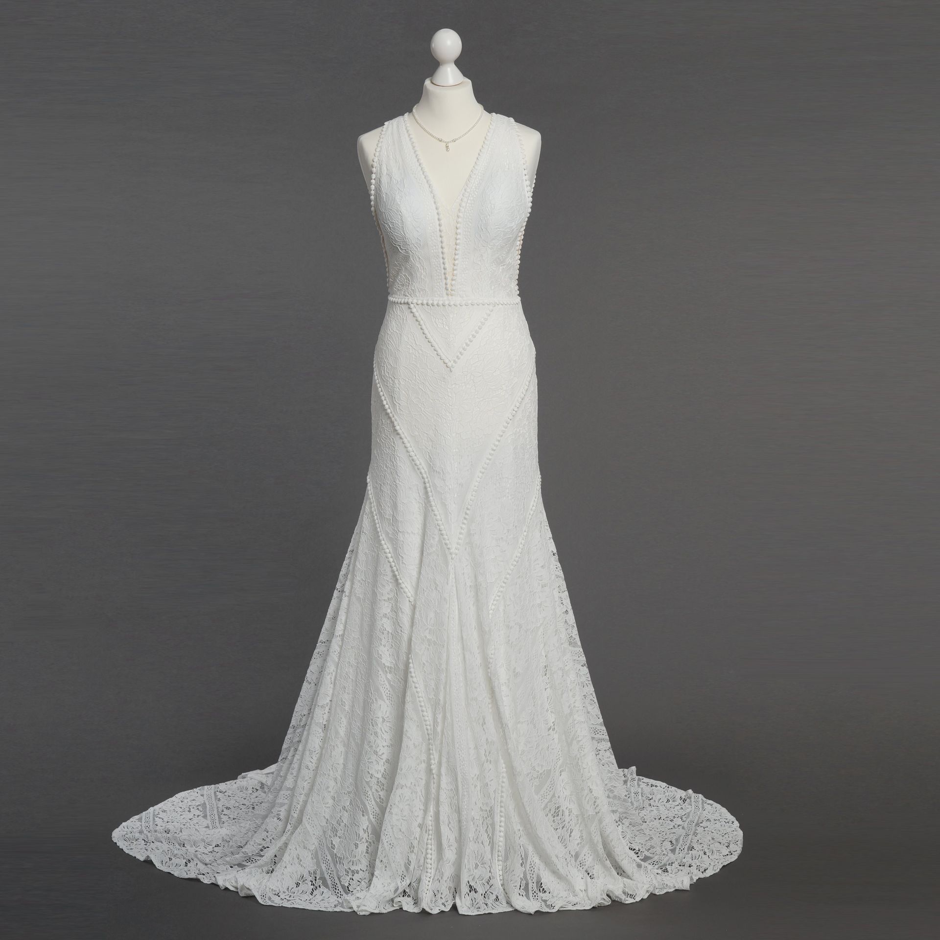 Ein weißes Spitzenbrautkleid hängt an einer Schaufensterpuppe