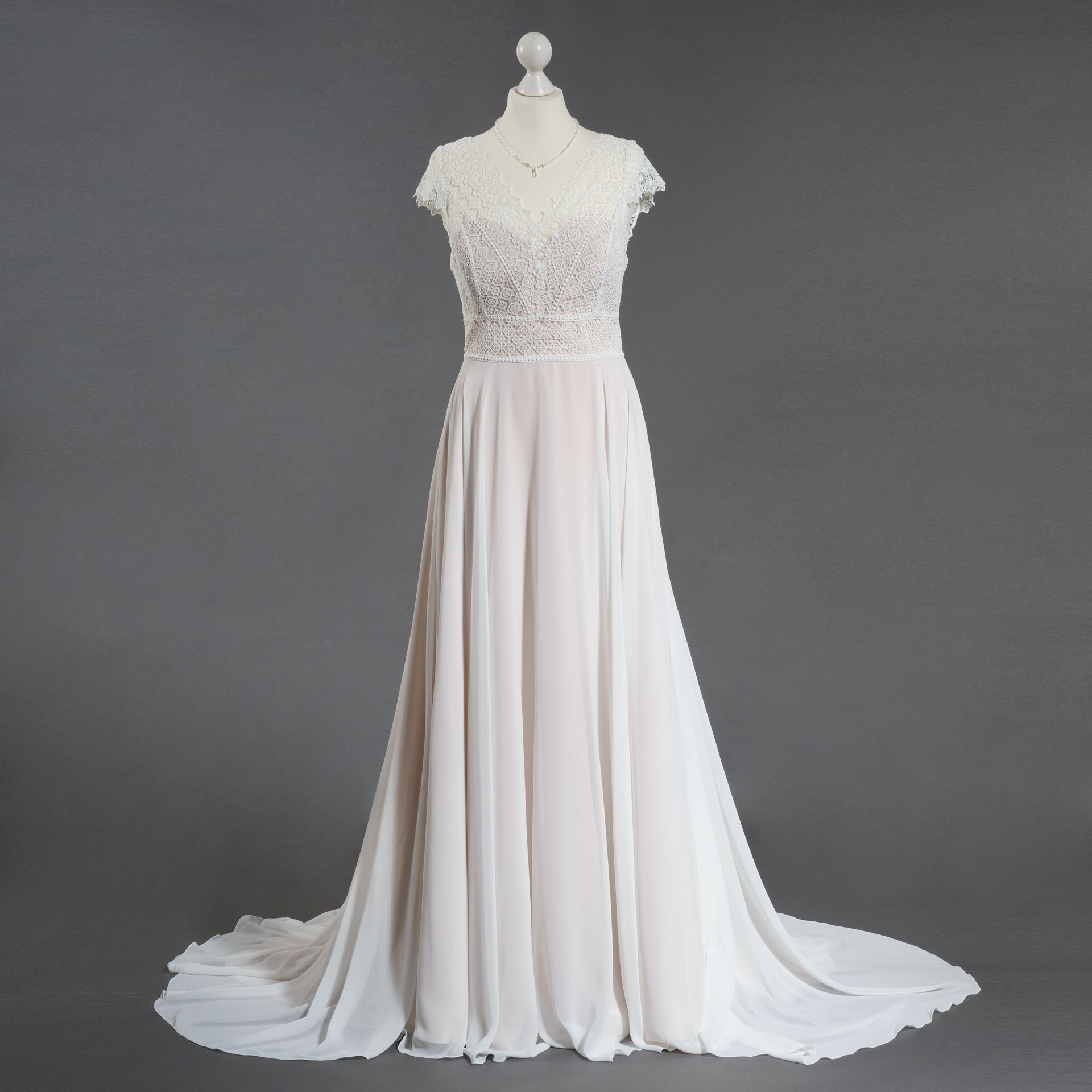 Ein weißes Brautkleid mit kurzen Ärmeln ist auf einer Schaufensterpuppe