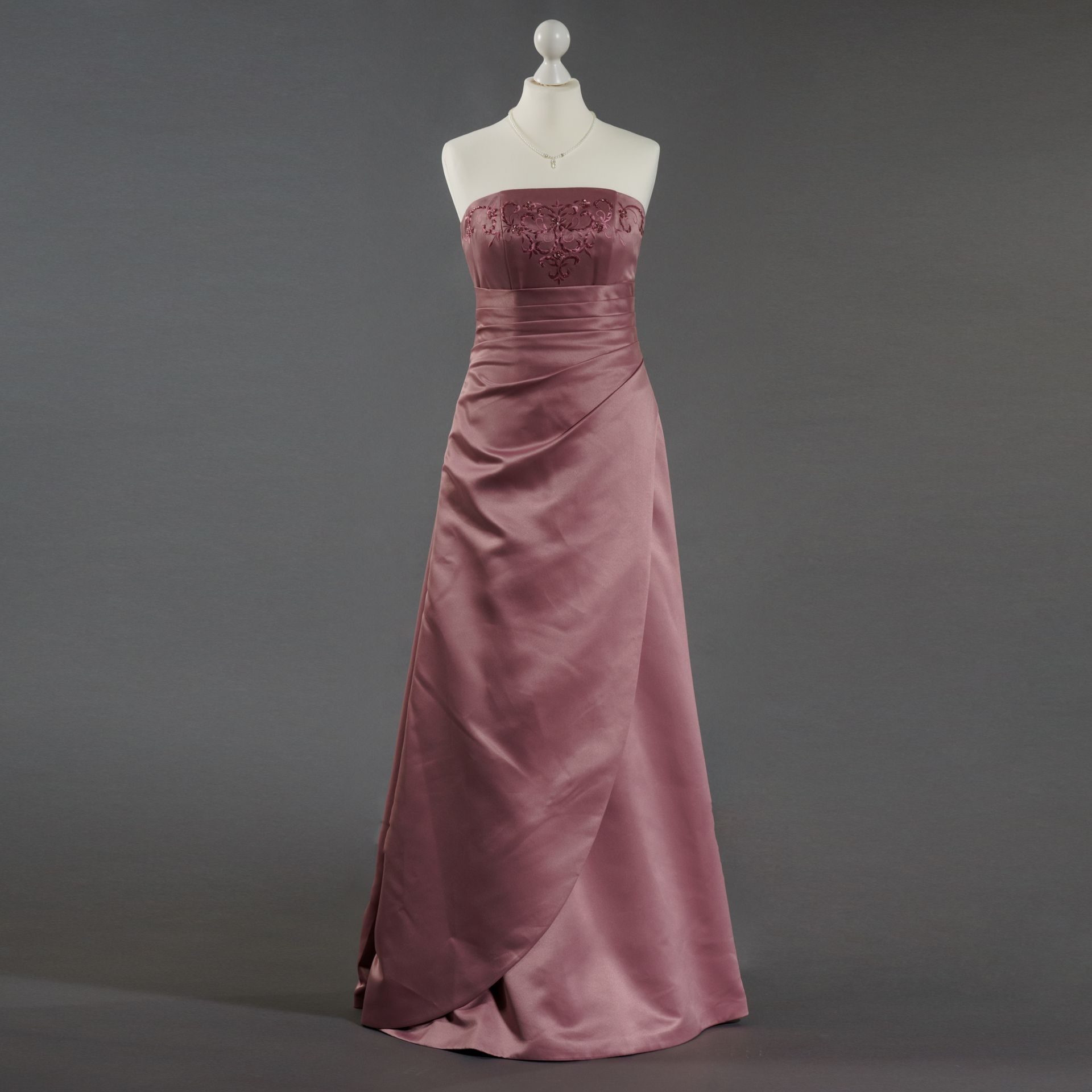 Ein rosa trägerloses Kleid hängt an einer Schaufensterpuppe