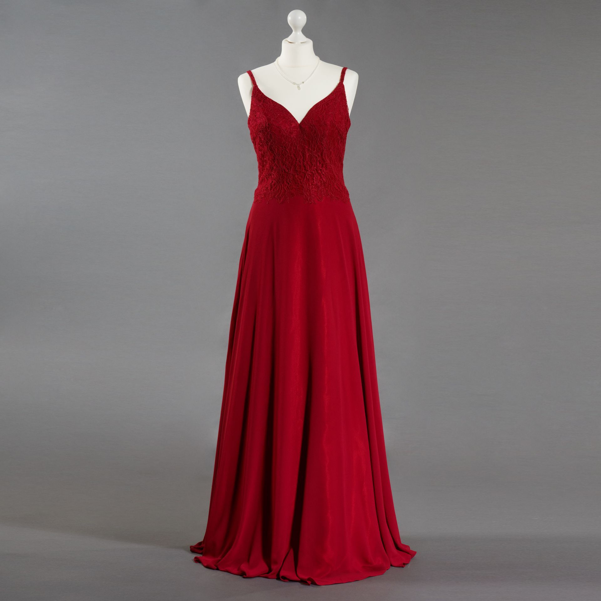 Ein rotes Kleid hängt auf einer Schaufensterpuppe mit grauem Hintergrund