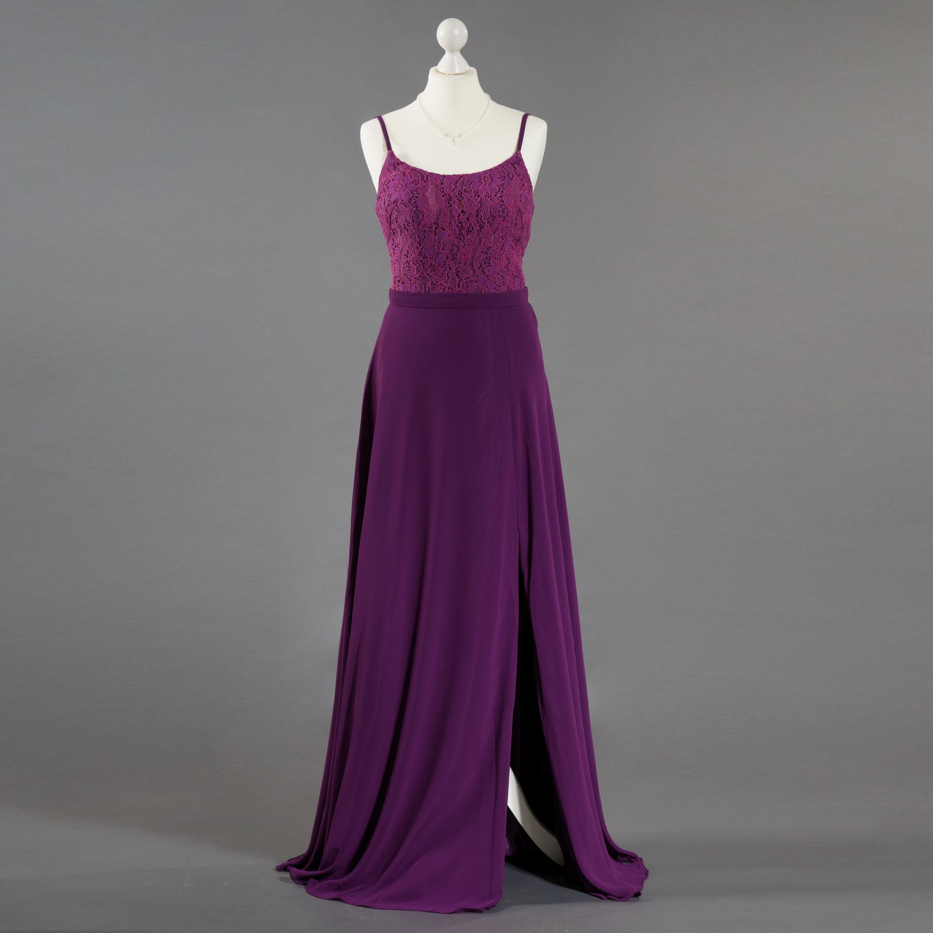 Ein lila Kleid hängt auf einer Schaufensterpuppe mit grauem Hintergrund