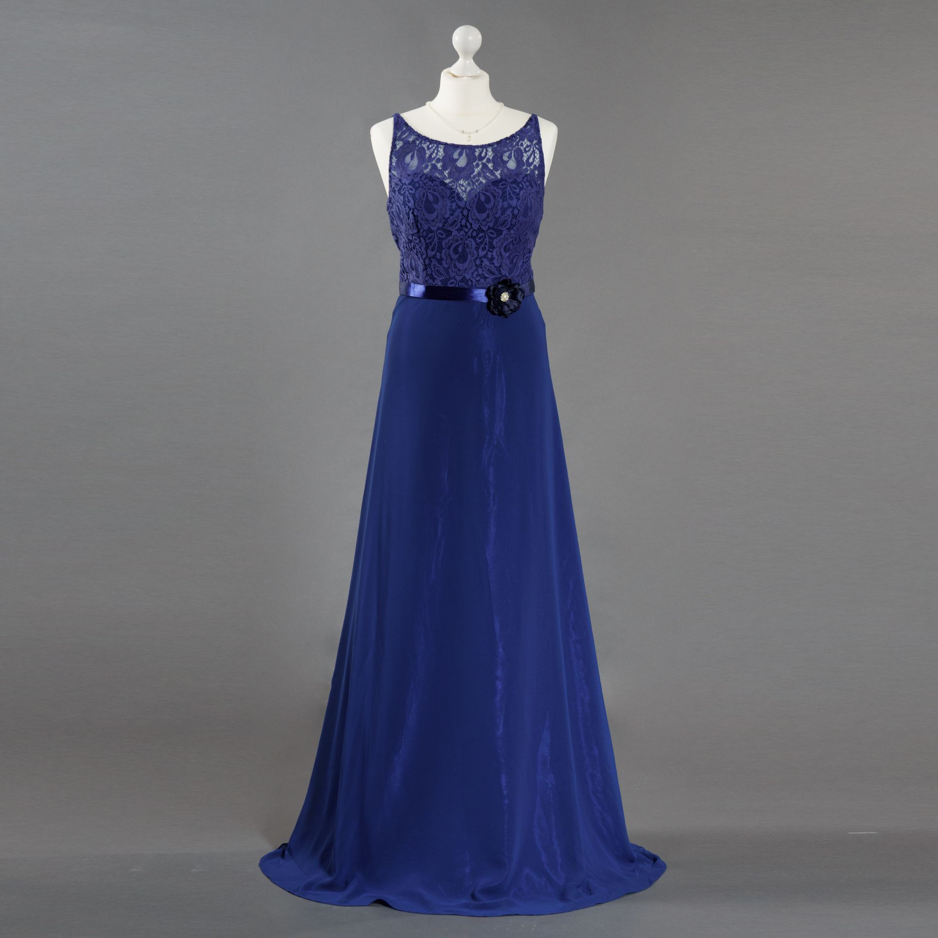 Ein blaues Kleid hängt an einer Schaufensterpuppe vor einem grauen Hintergrund