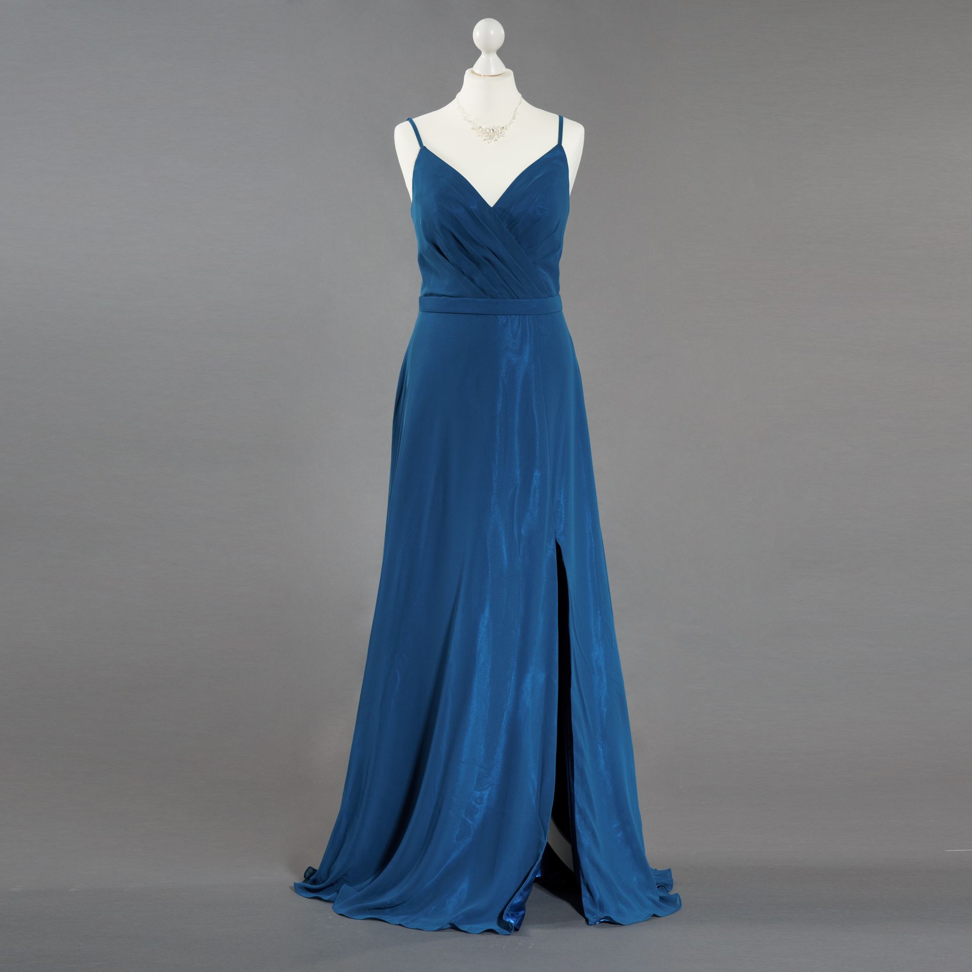 Ein blaues Kleid hängt an einer Schaufensterpuppe vor einem grauen Hintergrund