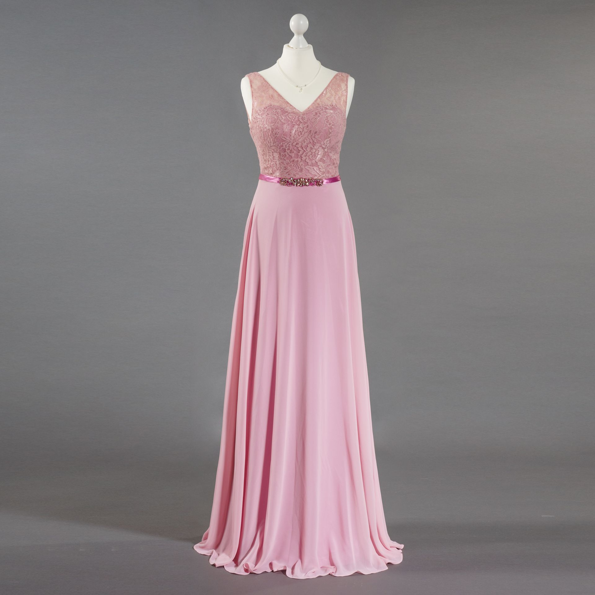 Ein rosa Kleid hängt auf einer Schaufensterpuppe mit grauem Hintergrund