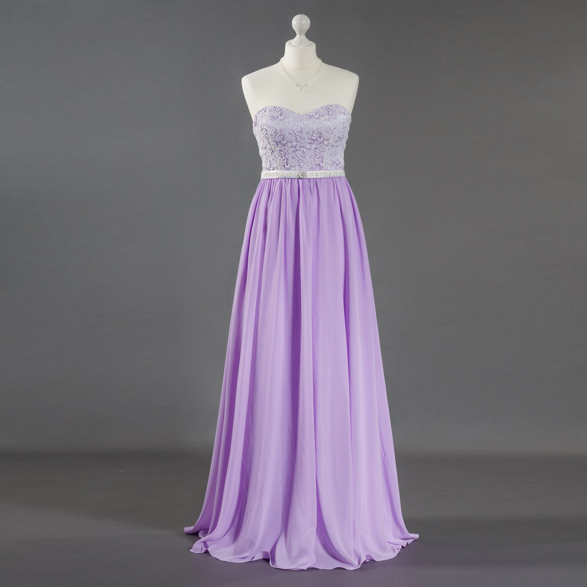 Ein lila Kleid hängt auf einer Schaufensterpuppe vor einem grauen Hintergrund