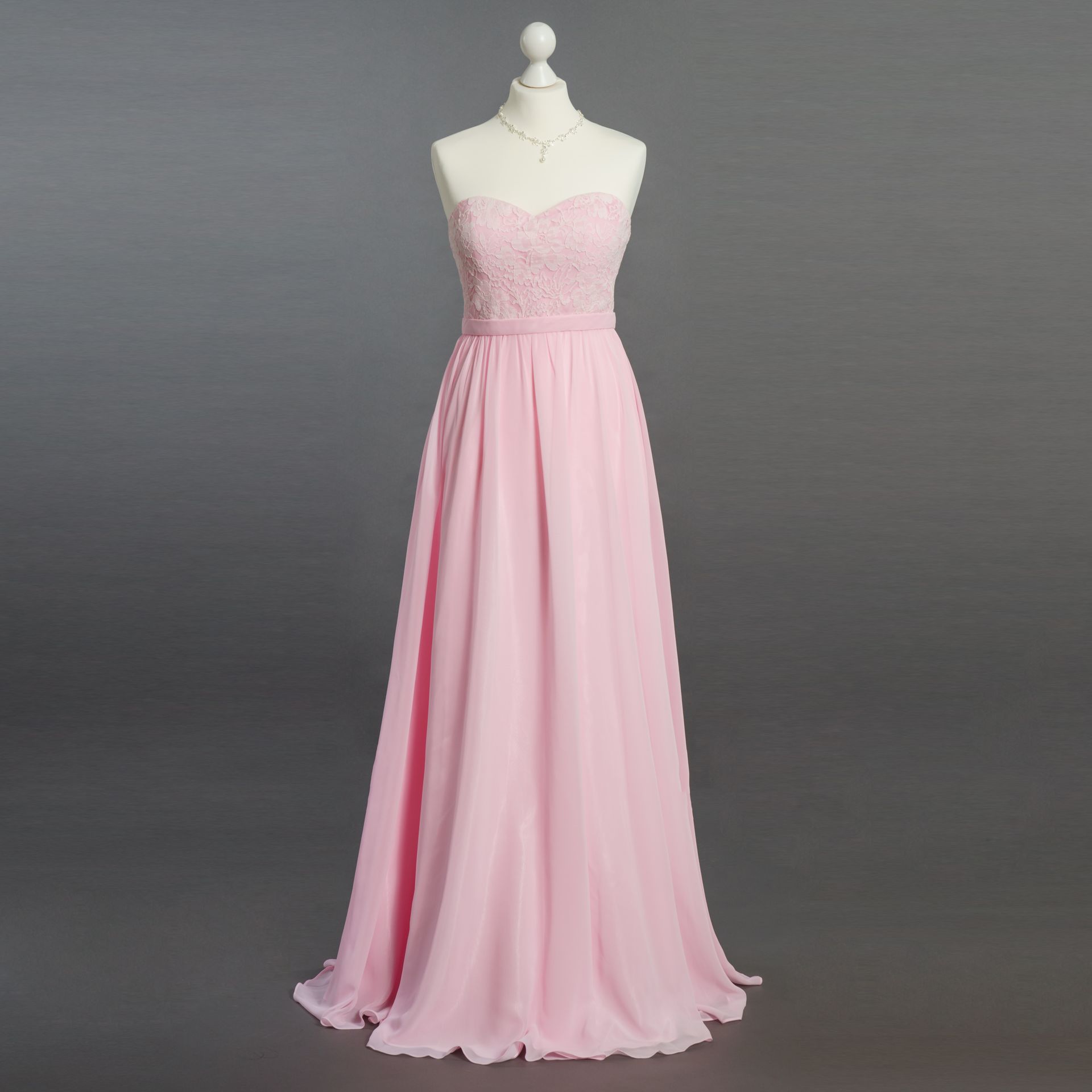 Ein rosa trägerloses Kleid hängt an einer Schaufensterpuppe