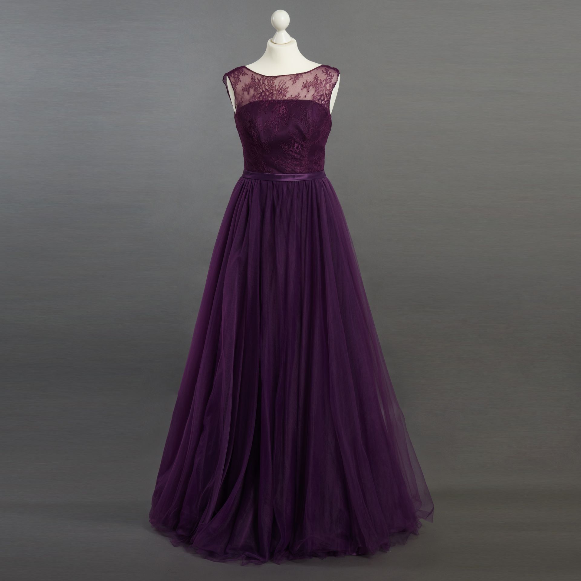 Ein lila Kleid hängt auf einer Schaufensterpuppe mit grauem Hintergrund