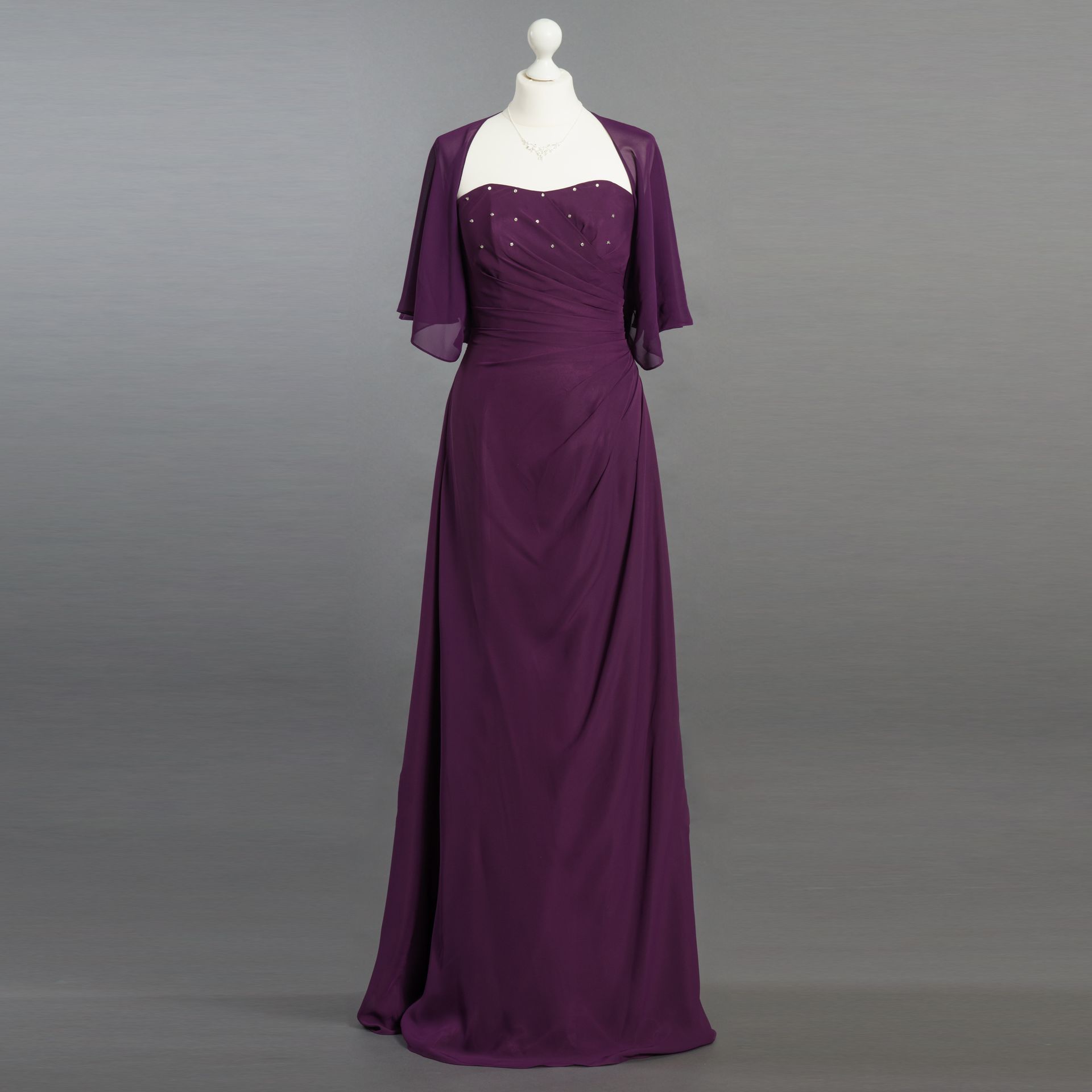 Ein lila Kleid mit einer weißen Jacke ist auf einer Schaufensterpuppe