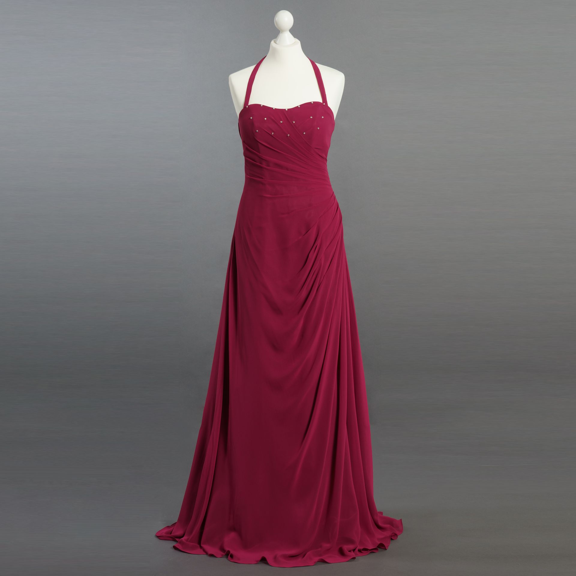 Ein rotes Kleid hängt auf einer Schaufensterpuppe mit grauem Hintergrund