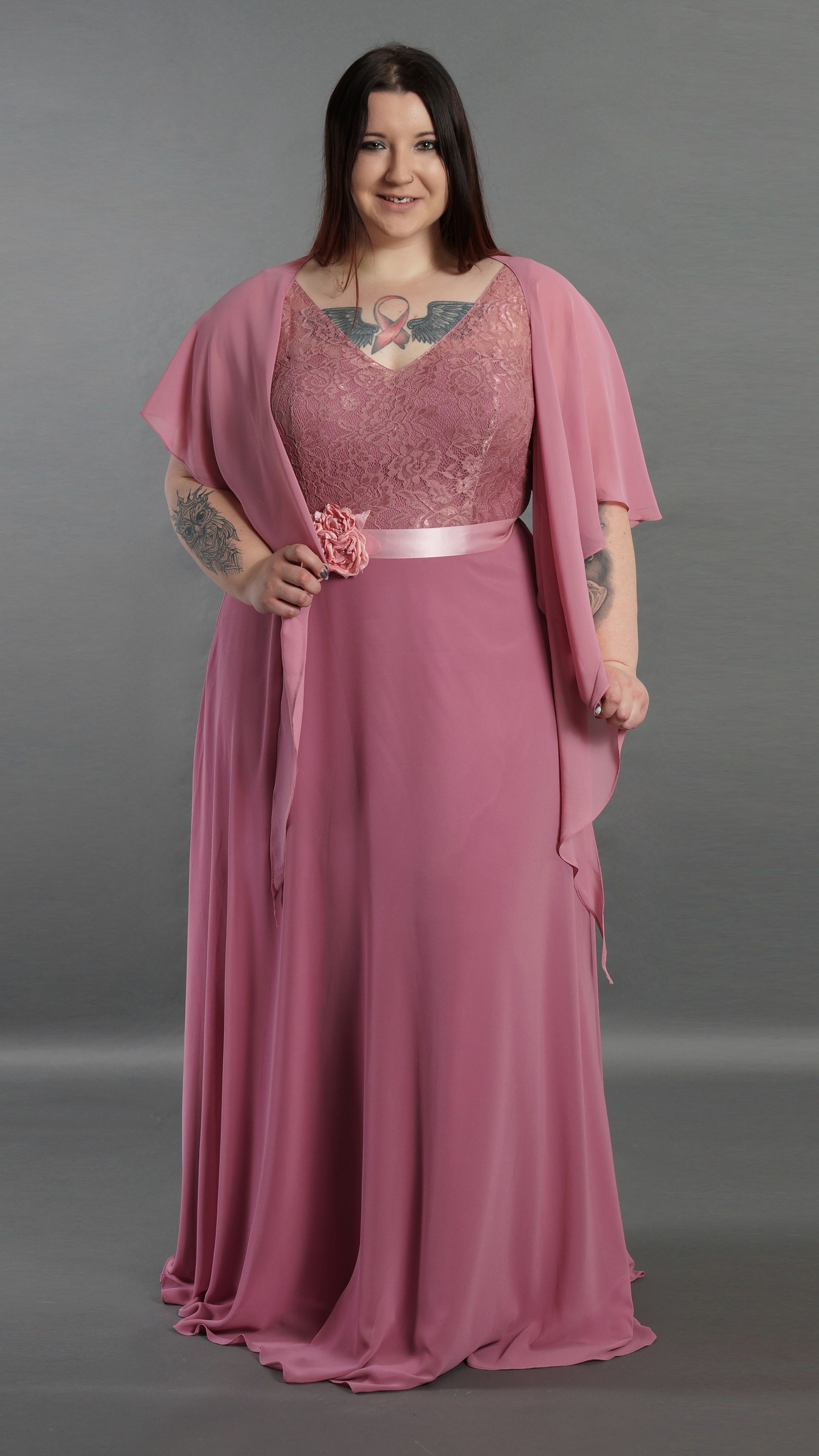 Eine Frau mit Übergröße trägt ein rosa Kleid und einen rosa Schal.
