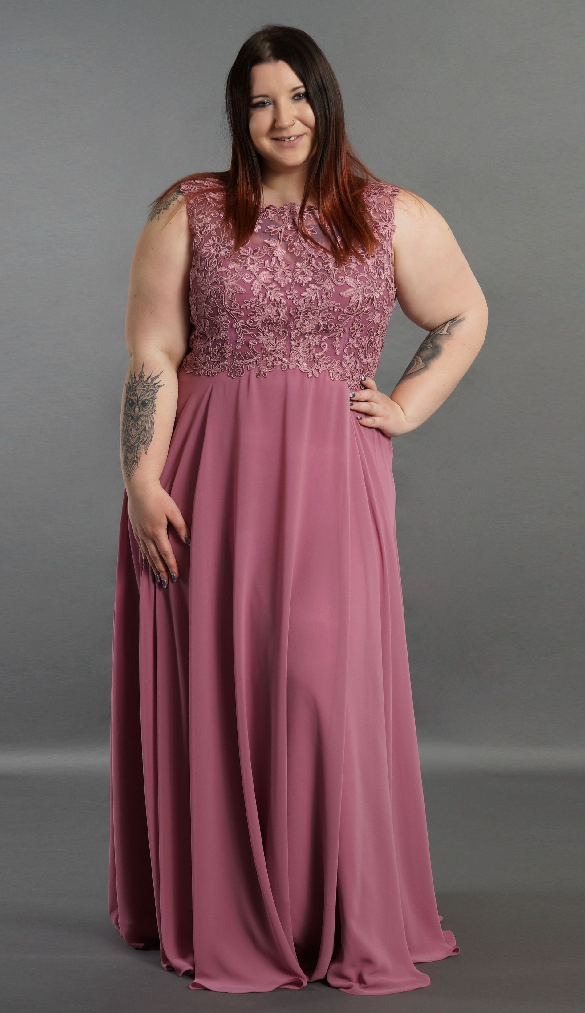 Eine Frau mit Übergröße trägt ein langes rosa Kleid.