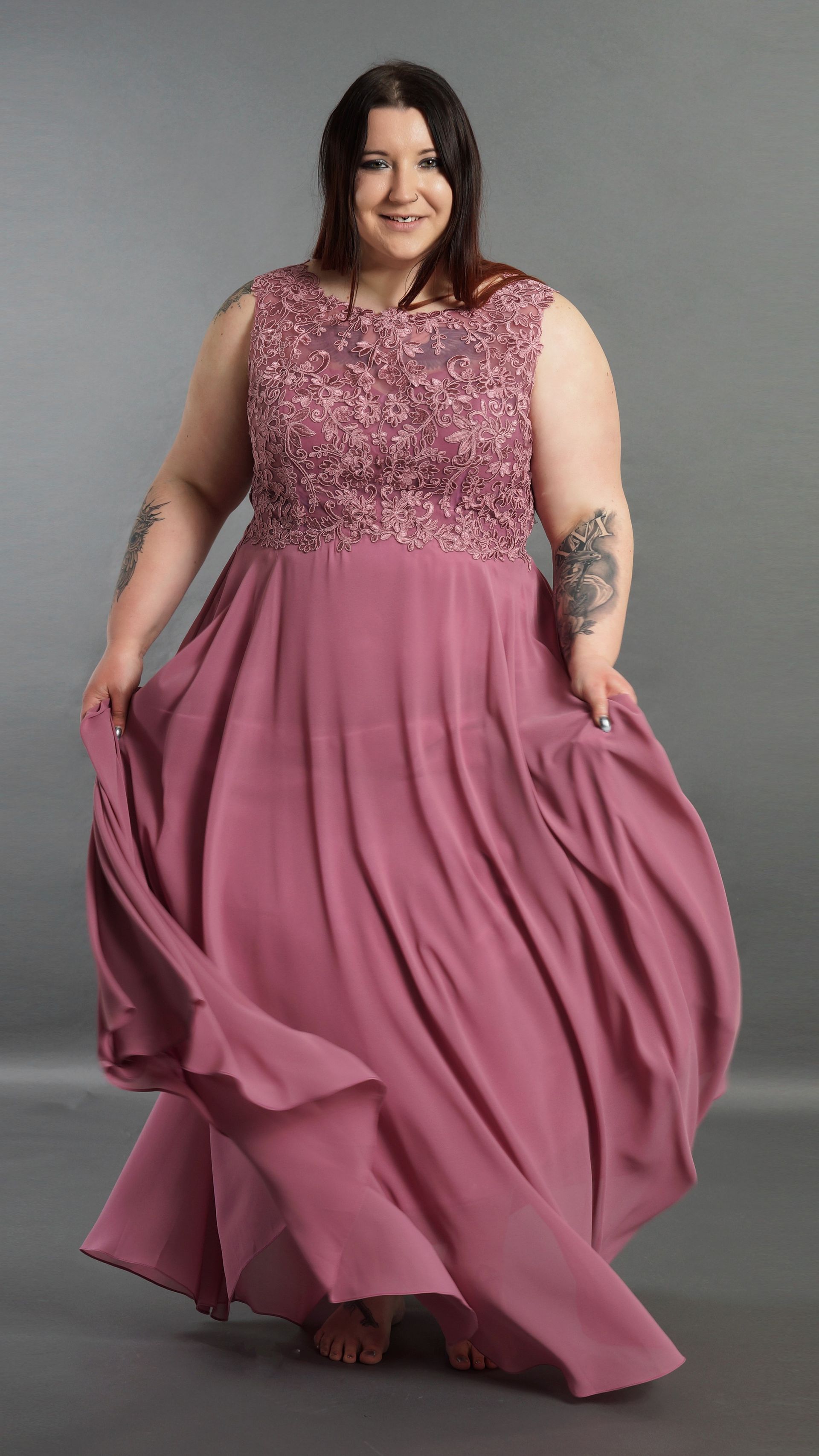 Eine Frau mit Übergröße trägt ein langes rosa Kleid.