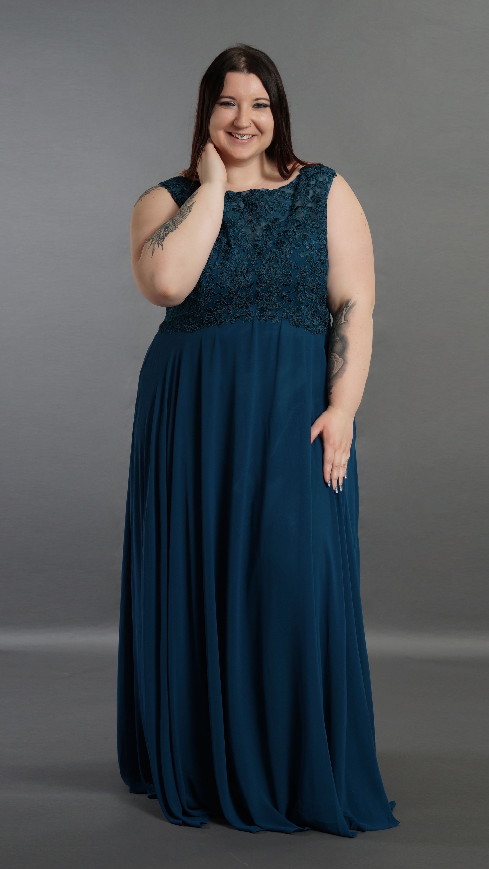 Eine Frau mit Übergröße trägt ein blaues Kleid und lächelt.