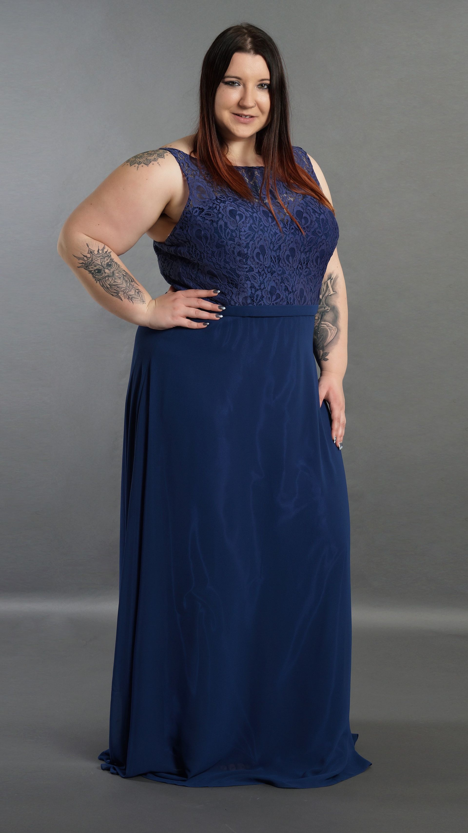 Eine Frau mit Übergröße steht in einem langen blauen Kleid da.