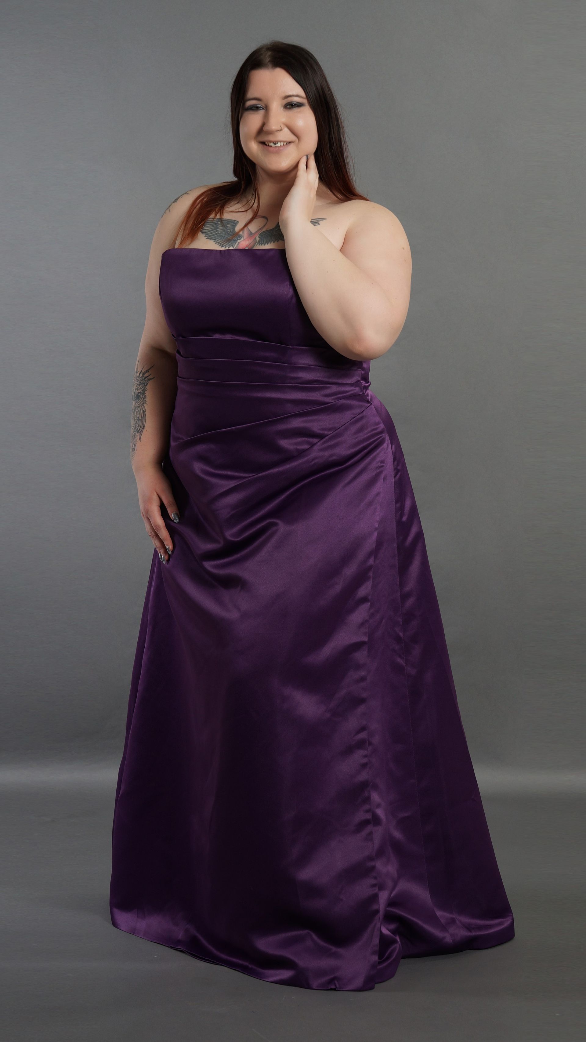 Eine Frau mit Übergröße trägt ein lila trägerloses Kleid.