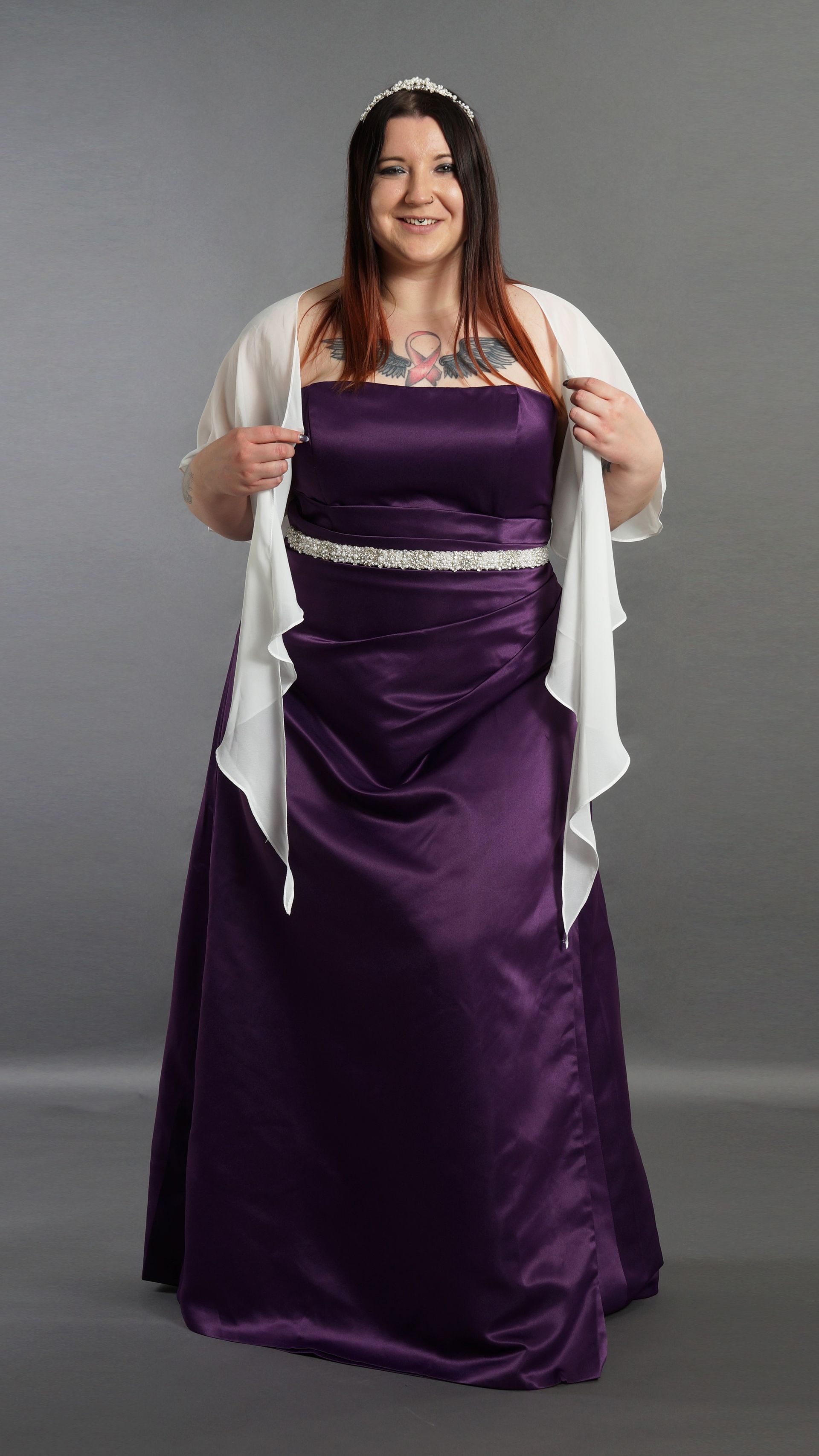 Eine Frau trägt ein lila Kleid und eine weiße Jacke.