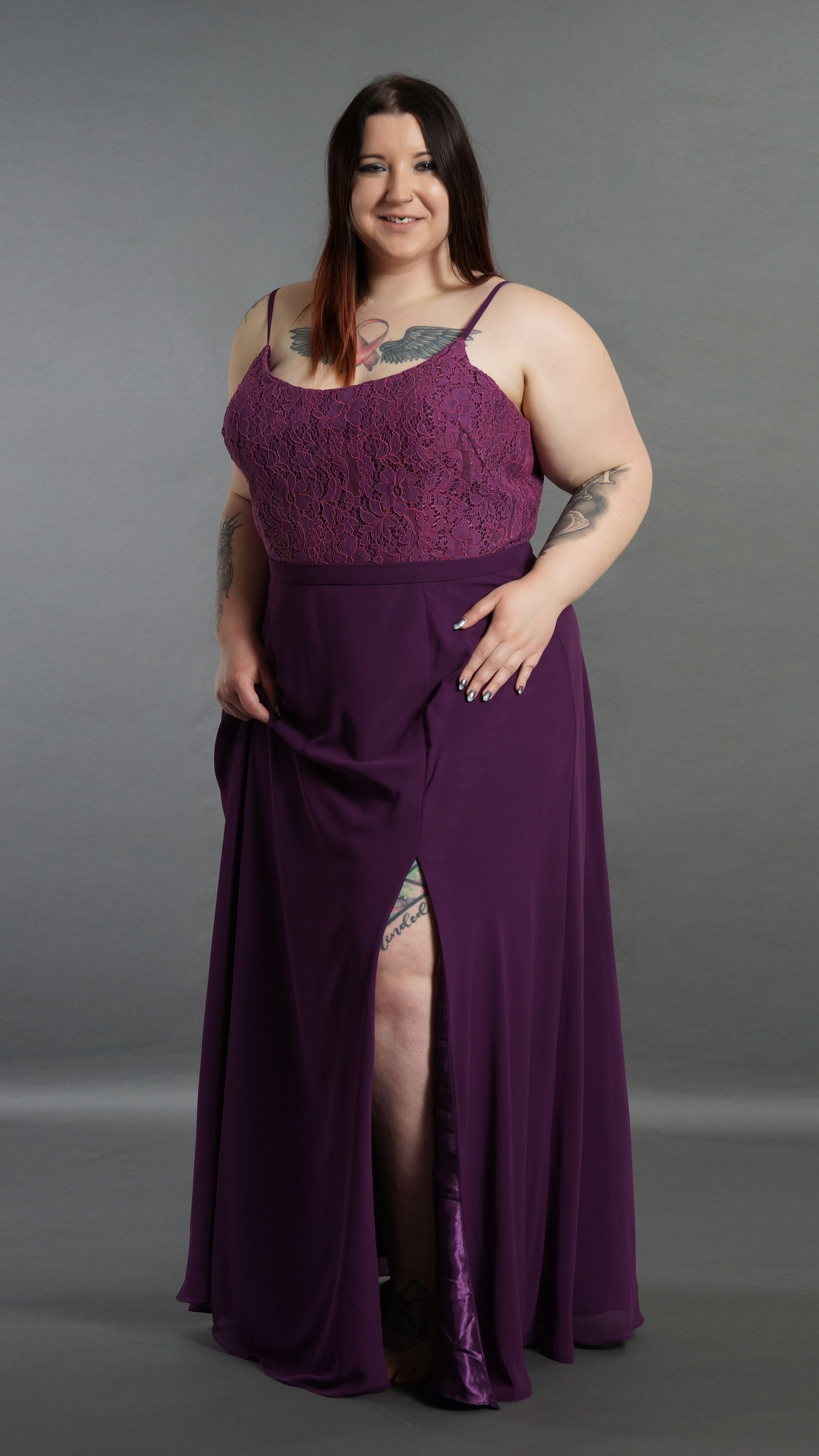 Eine Frau mit Übergröße trägt ein lila Kleid mit hohem Schlitz.