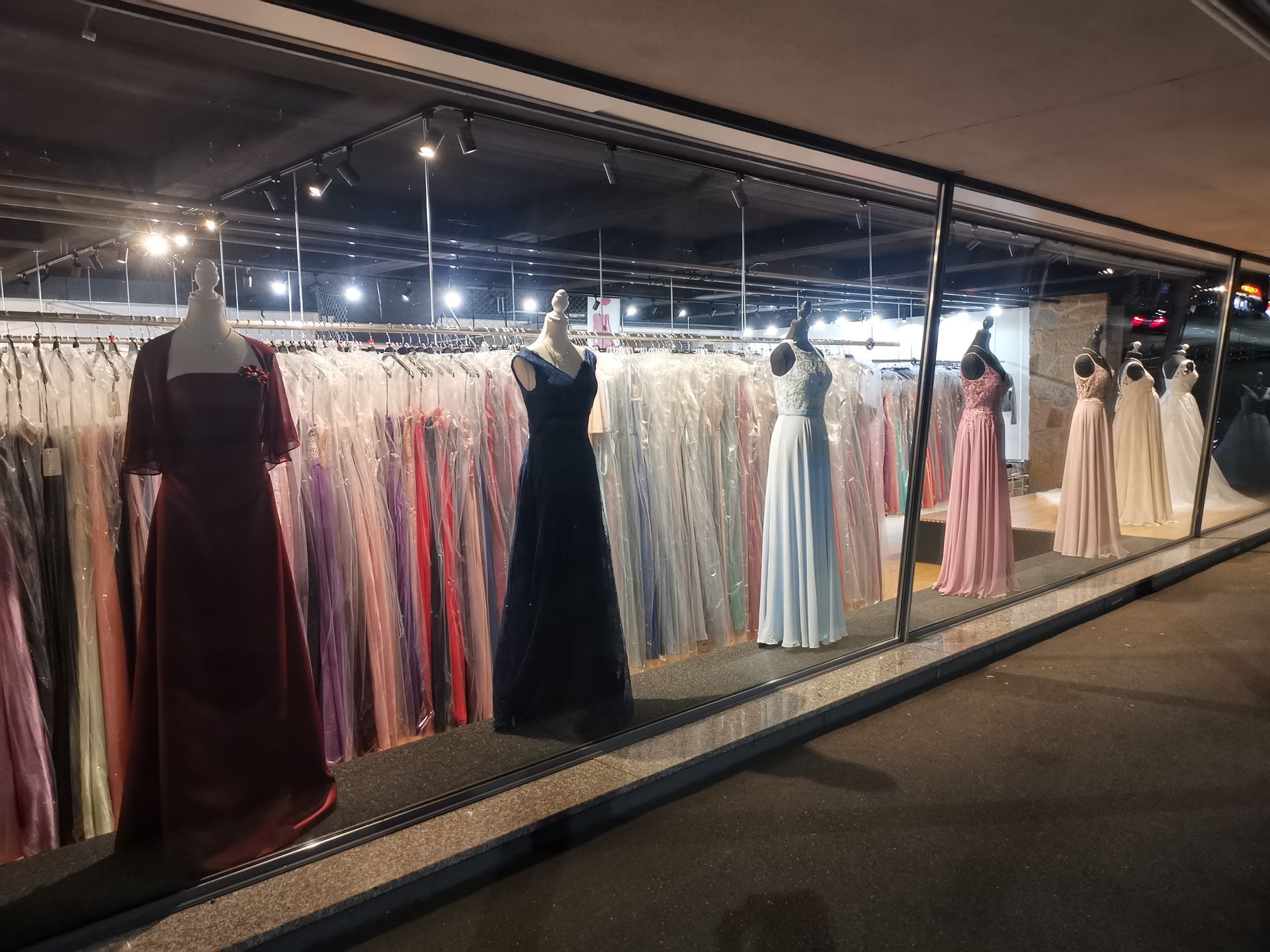 Eine Reihe Kleider hängt in einem Geschäft an einer Stange.