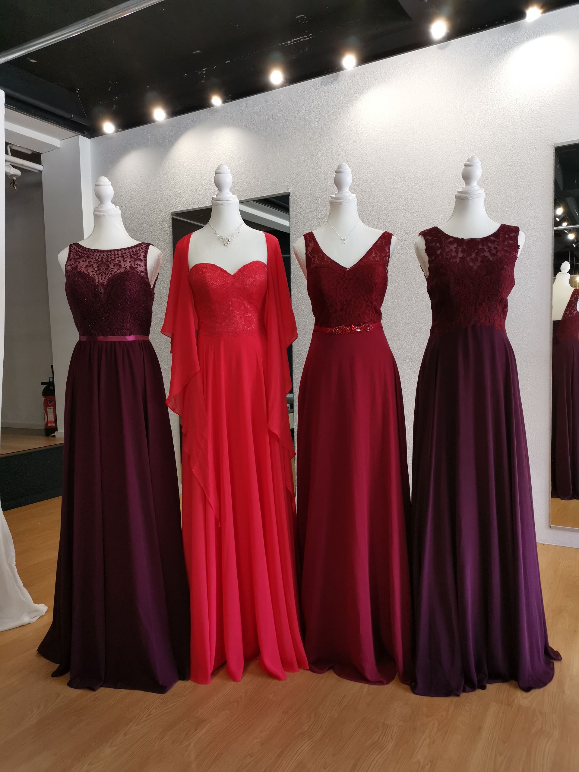 In einem Geschäft sind mehrere Brautjungfernkleider auf Schaufensterpuppen aufgereiht.