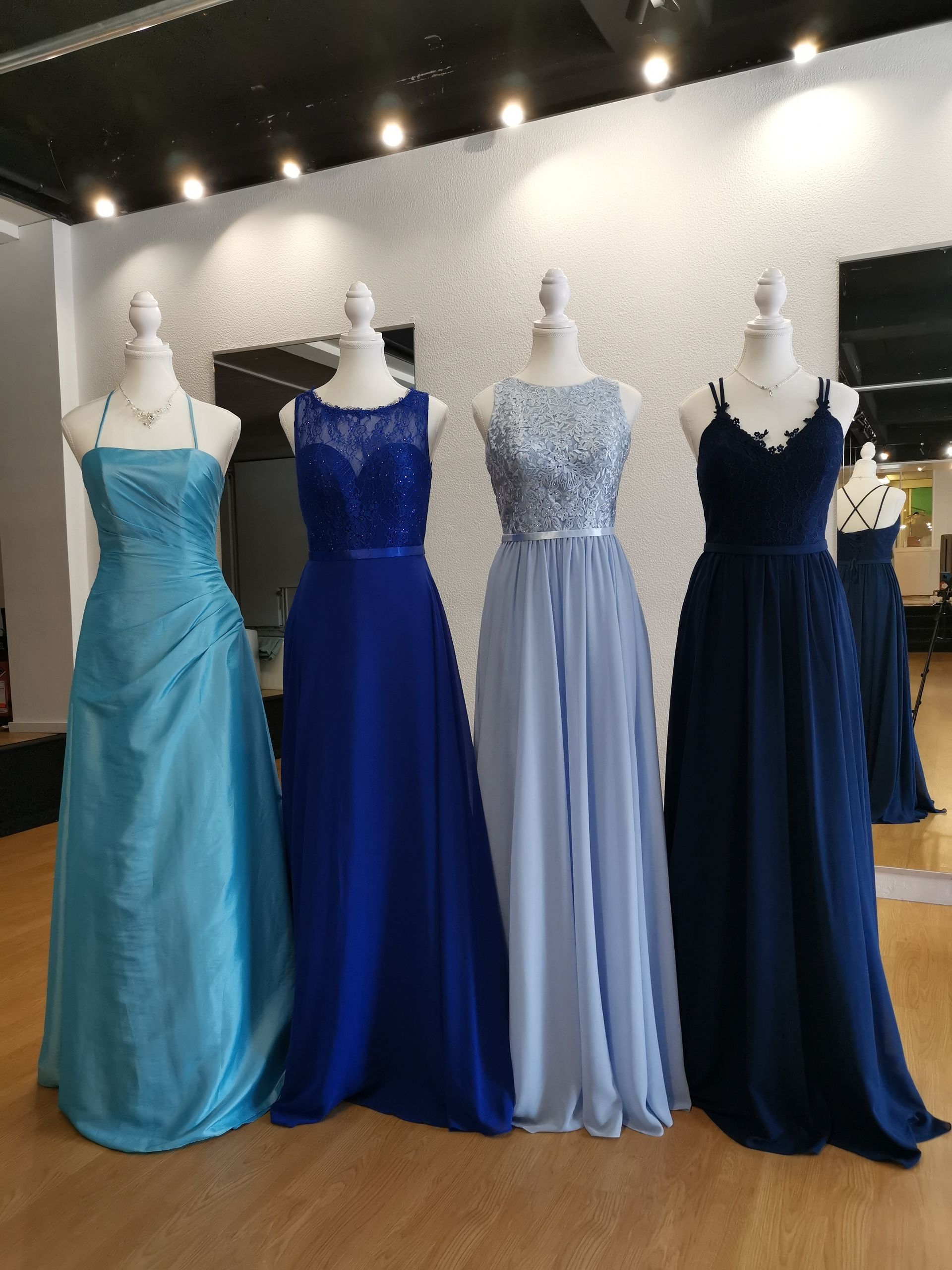 In einem Geschäft sind mehrere Kleider auf Schaufensterpuppen aufgereiht.