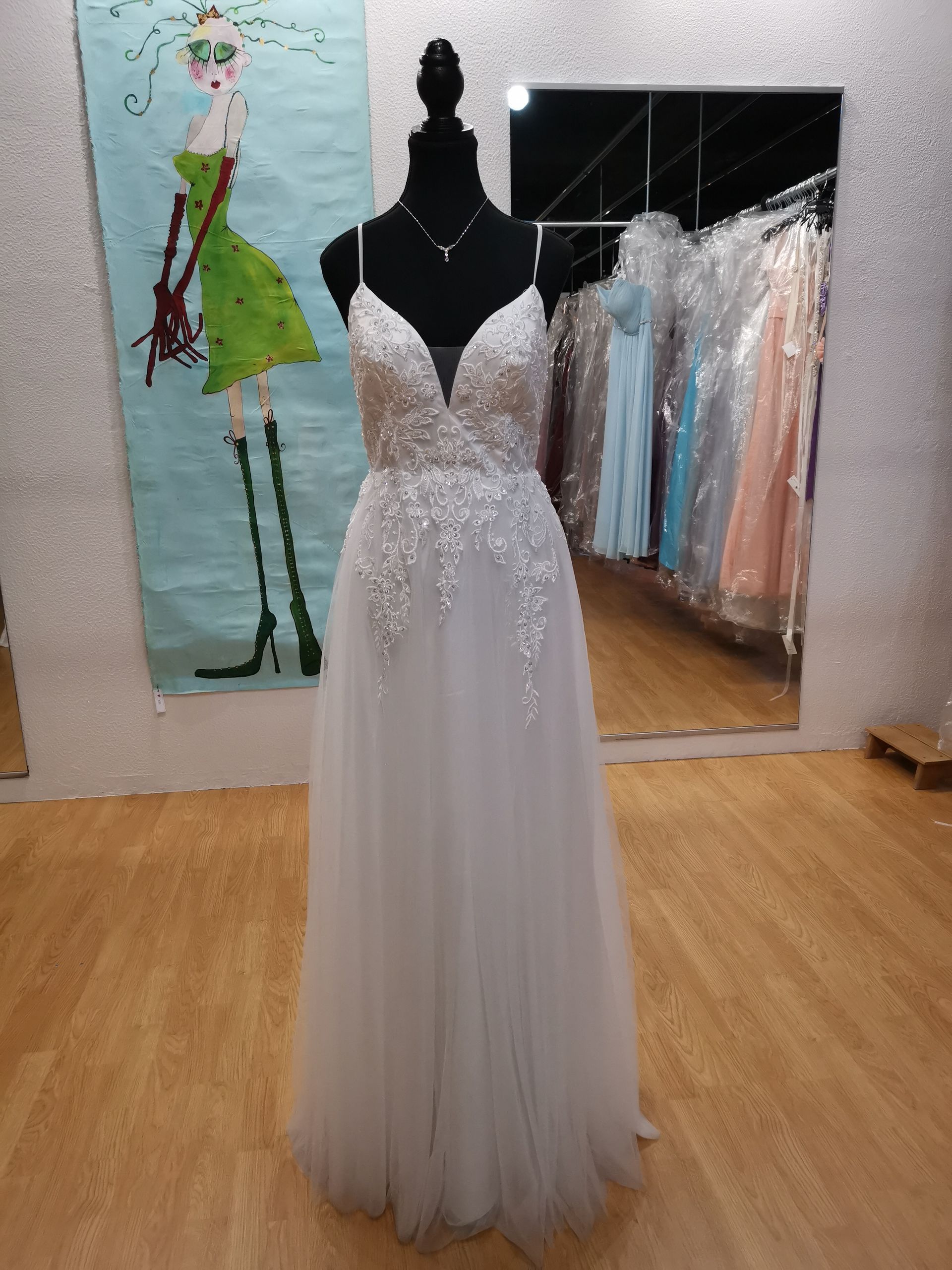 In einem Raum hängt an einer Schaufensterpuppe ein weißes Kleid.