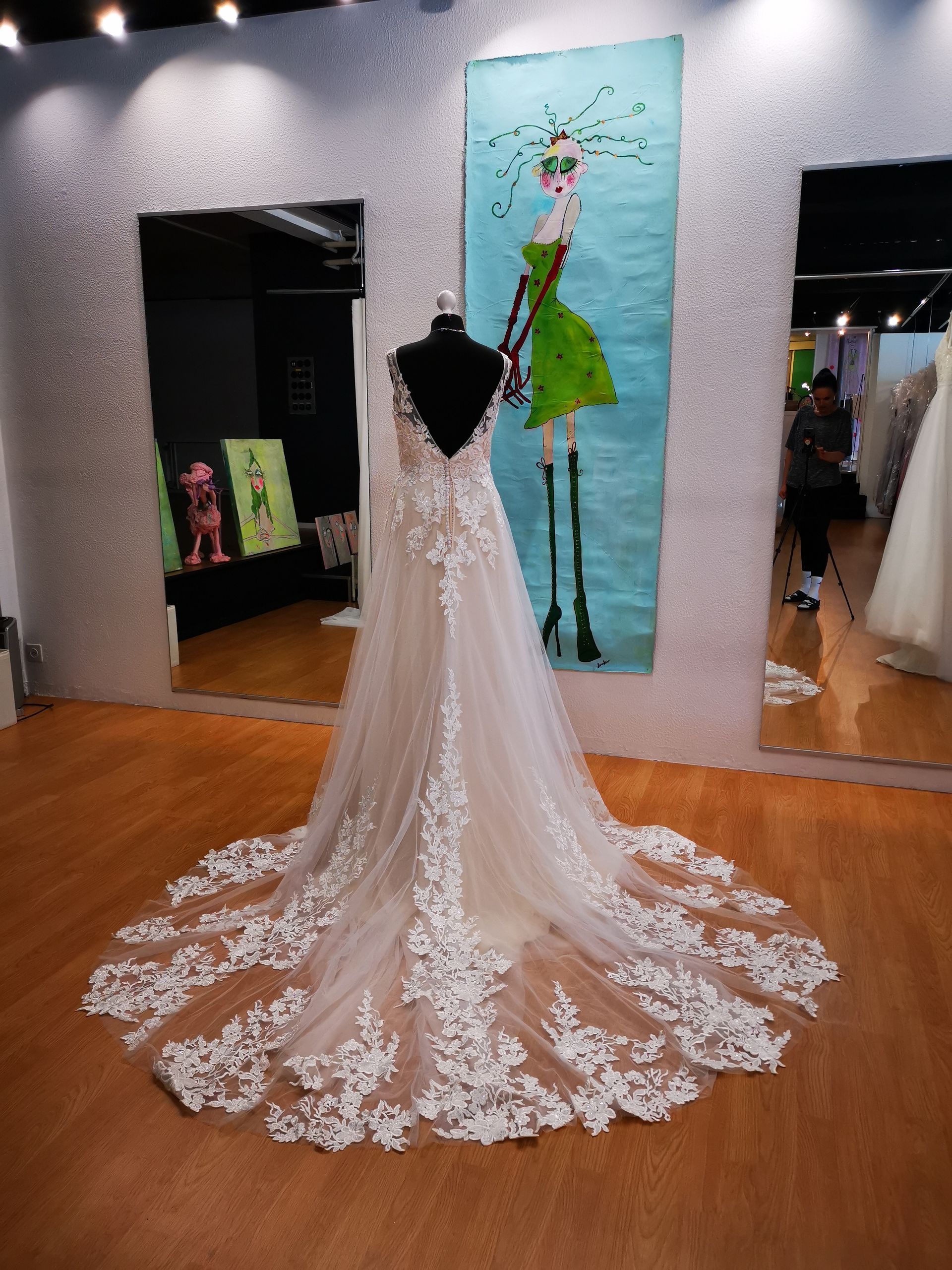 Vor einem Gemälde hängt ein Brautkleid auf einer Schaufensterpuppe.