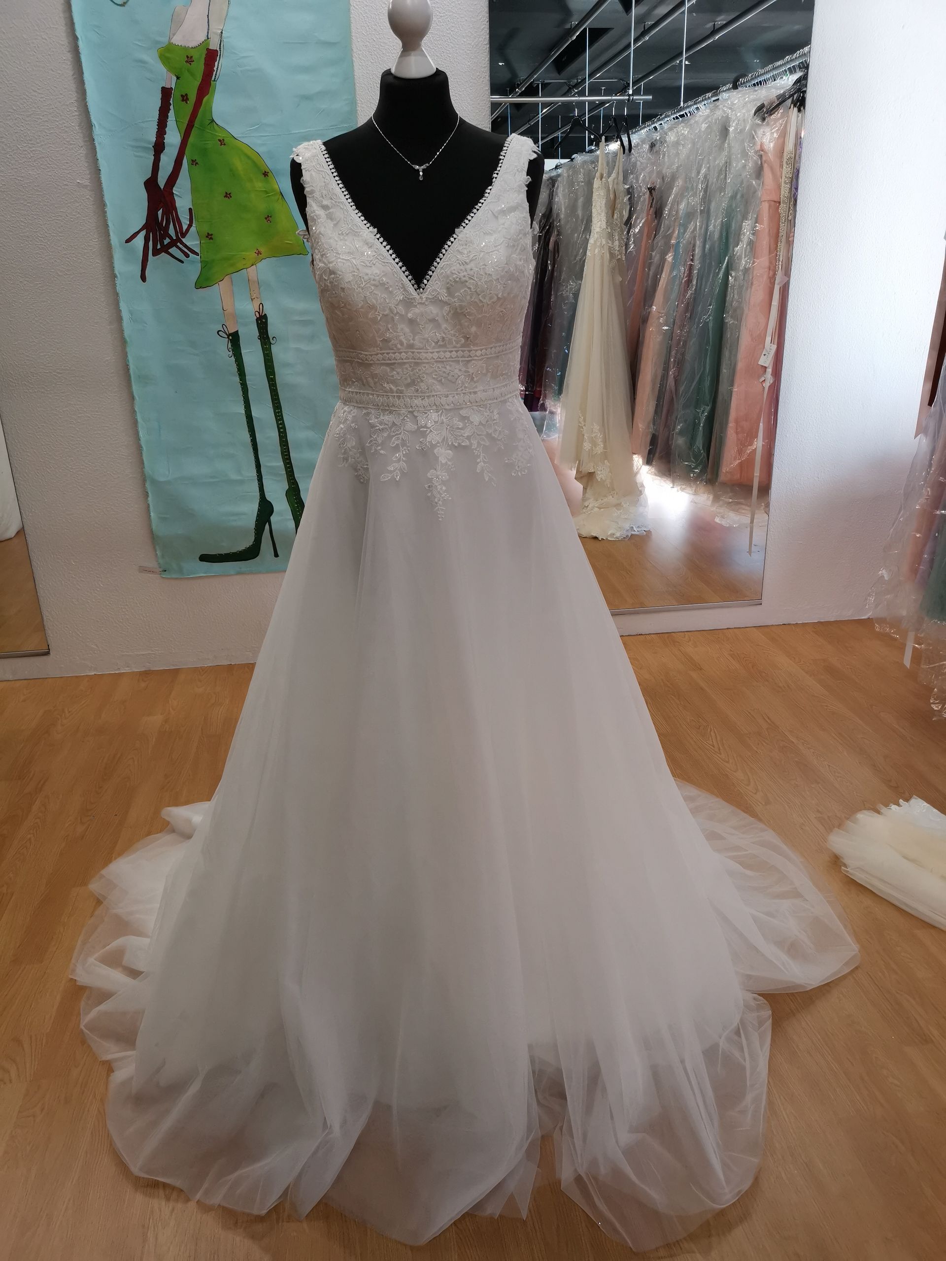 In einem Geschäft hängt an einer Schaufensterpuppe ein weißes Brautkleid.