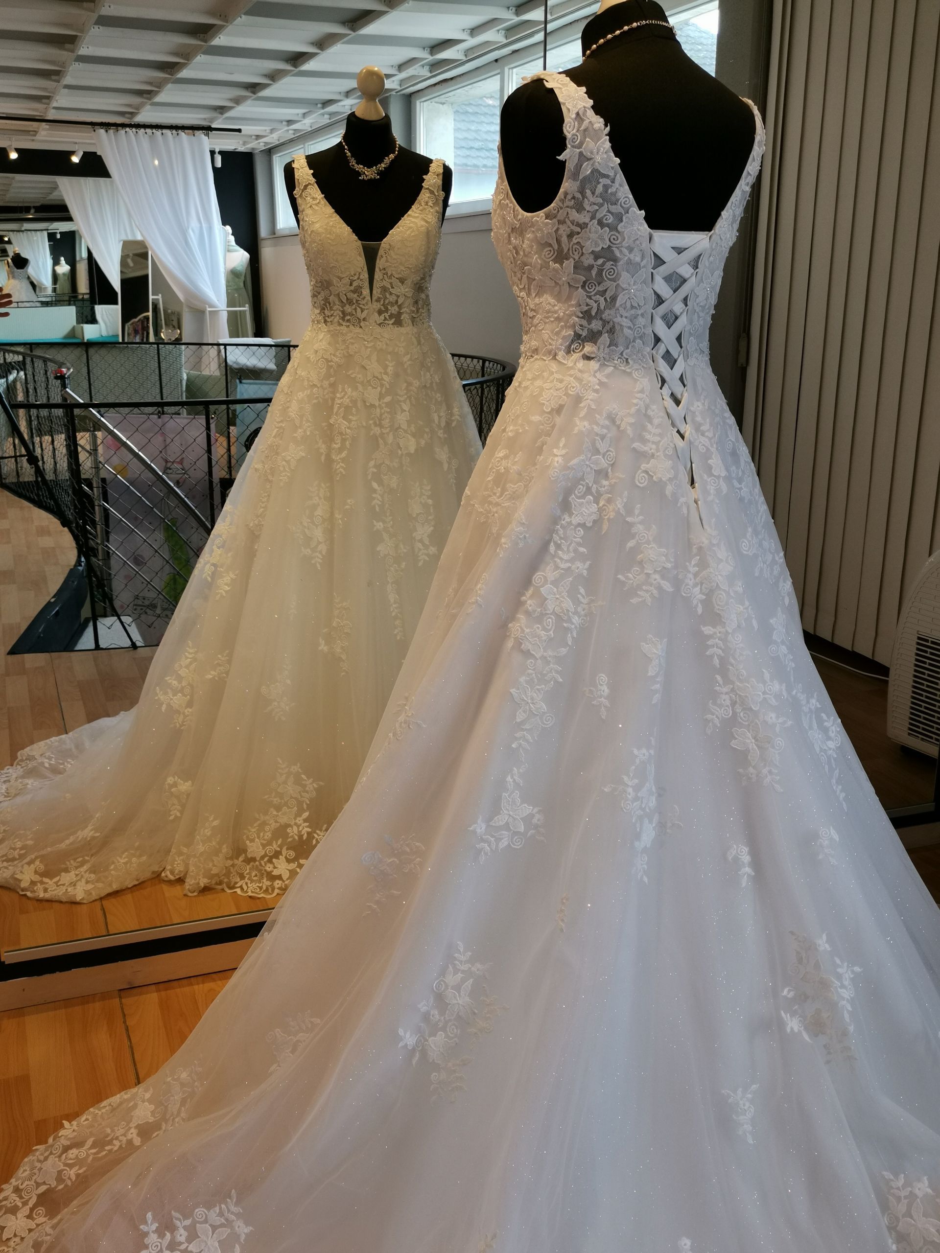 Ein Brautkleid hängt an einer Schaufensterpuppe vor einem Spiegel.