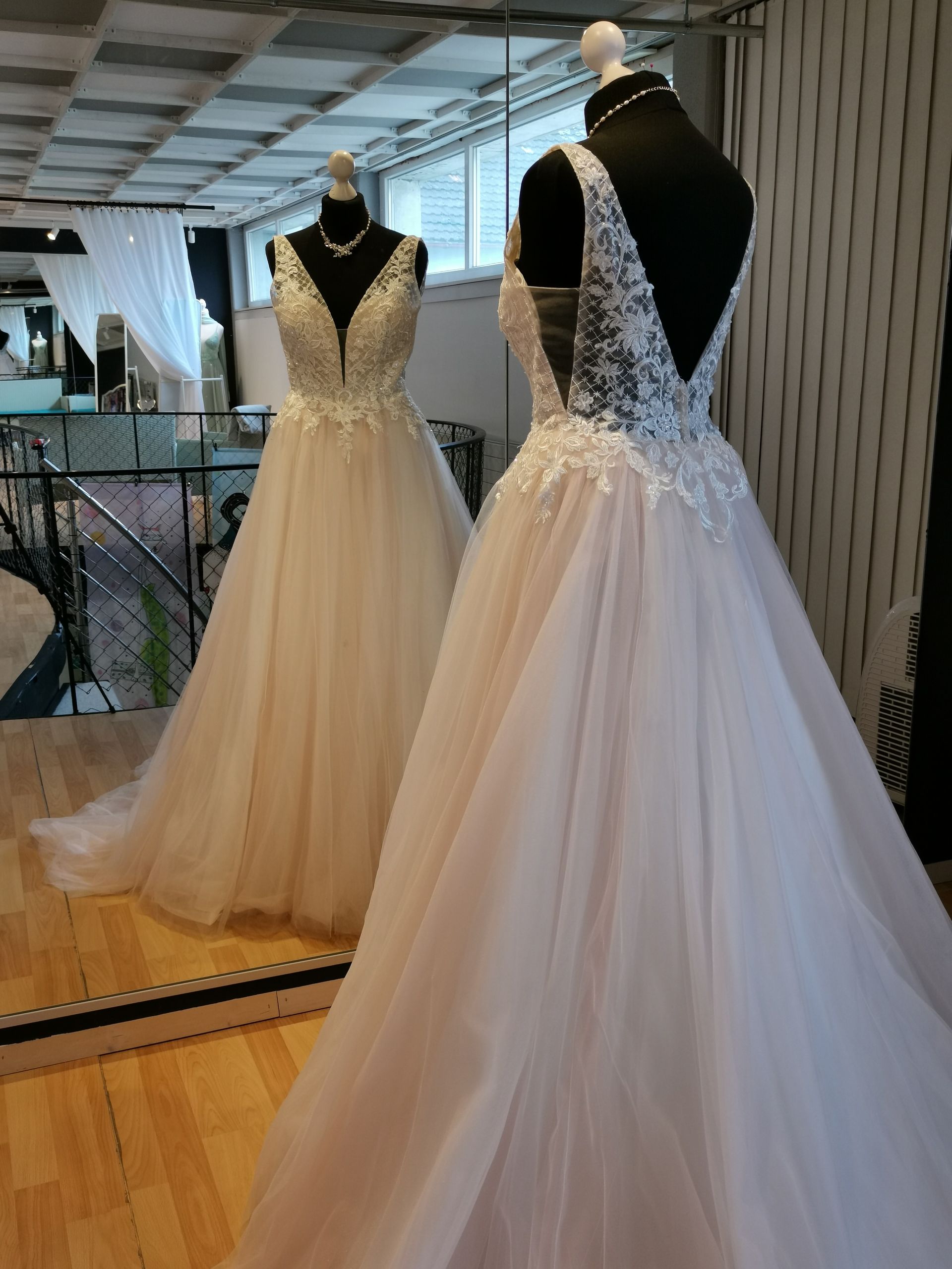 Ein Brautkleid hängt an einer Schaufensterpuppe vor einem Spiegel.