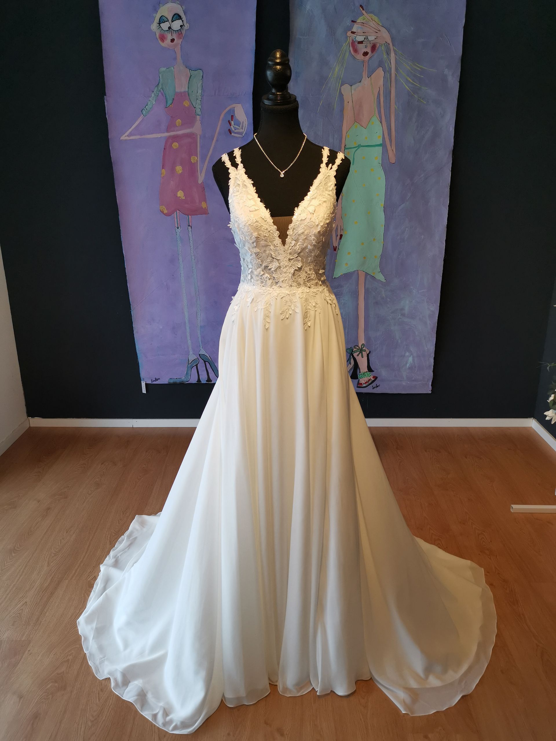 Vor einem Gemälde hängt an einer Schaufensterpuppe ein weißes Brautkleid.