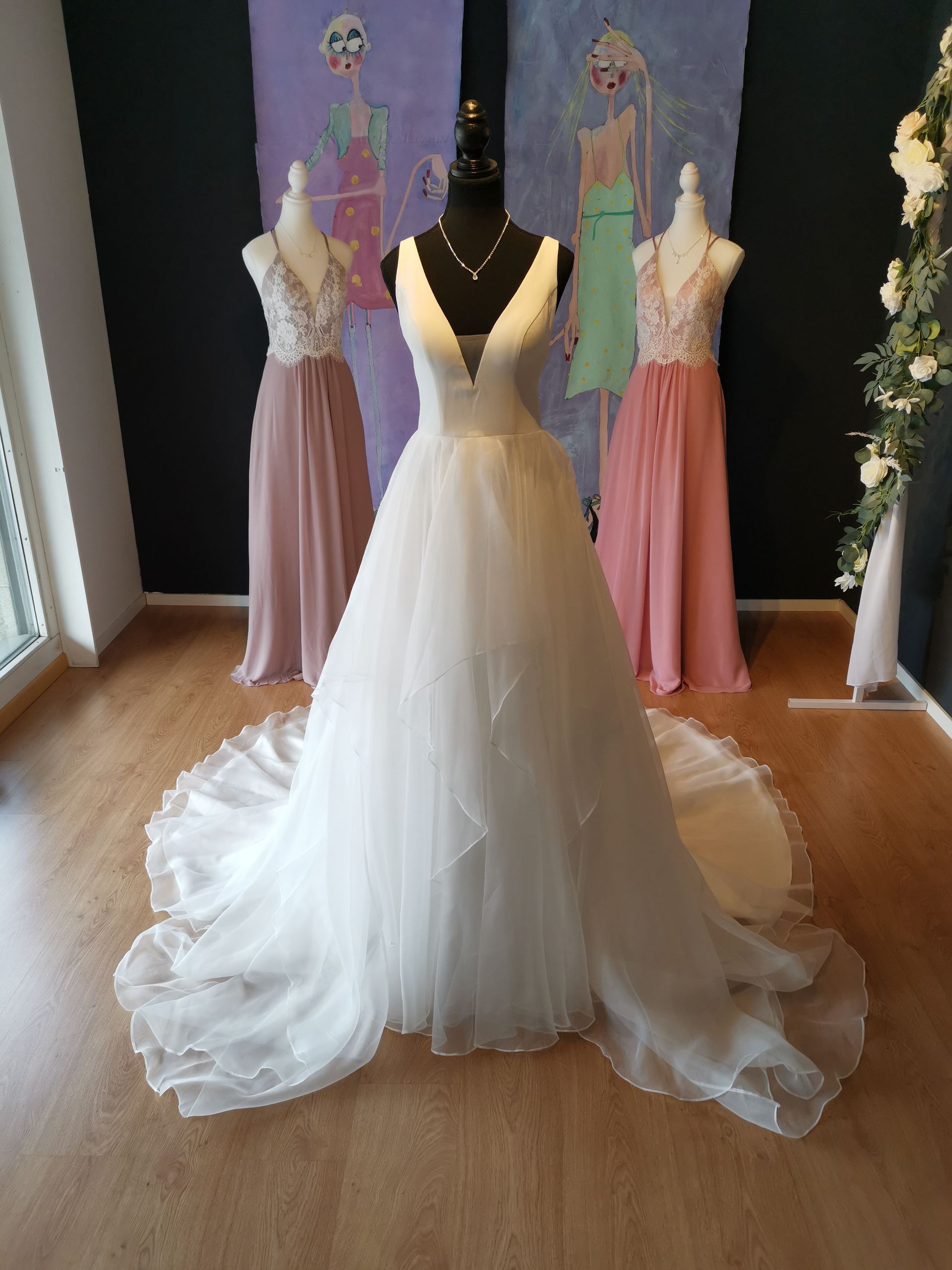 In einem Raum hängt ein weißes Brautkleid an einer Schaufensterpuppe.