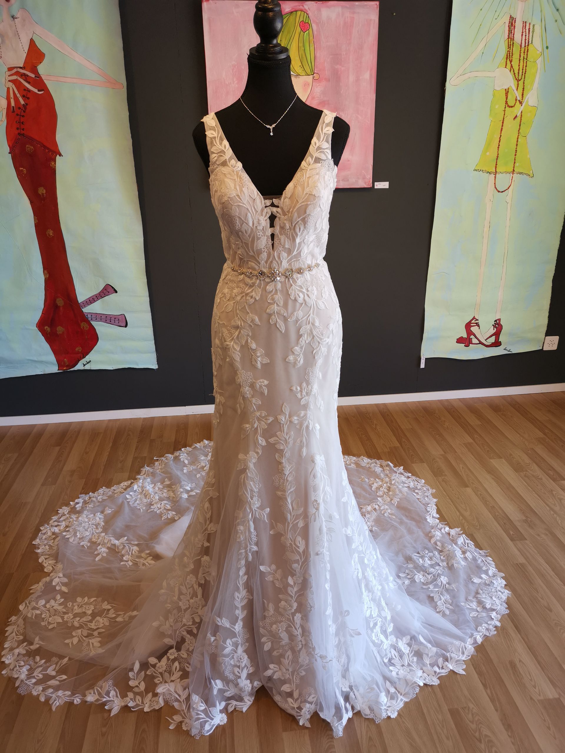 Ein Brautkleid hängt an einer Schaufensterpuppe vor Gemälden