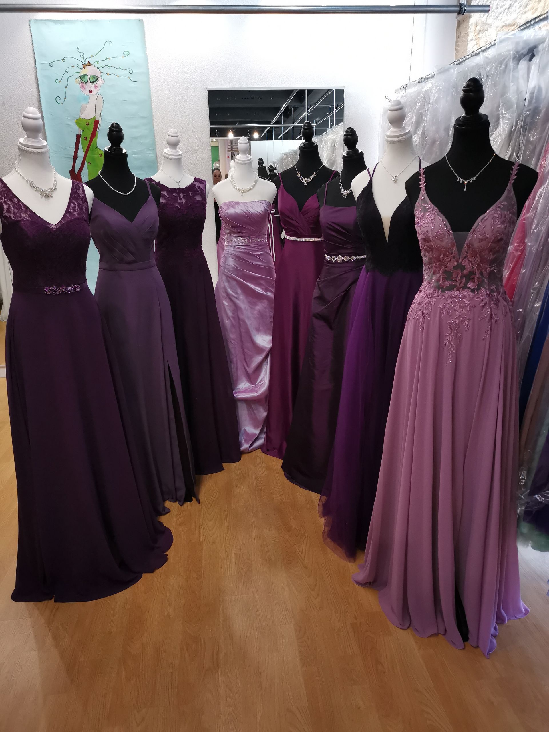 Eine Reihe lila Kleider auf Schaufensterpuppen in einem Geschäft